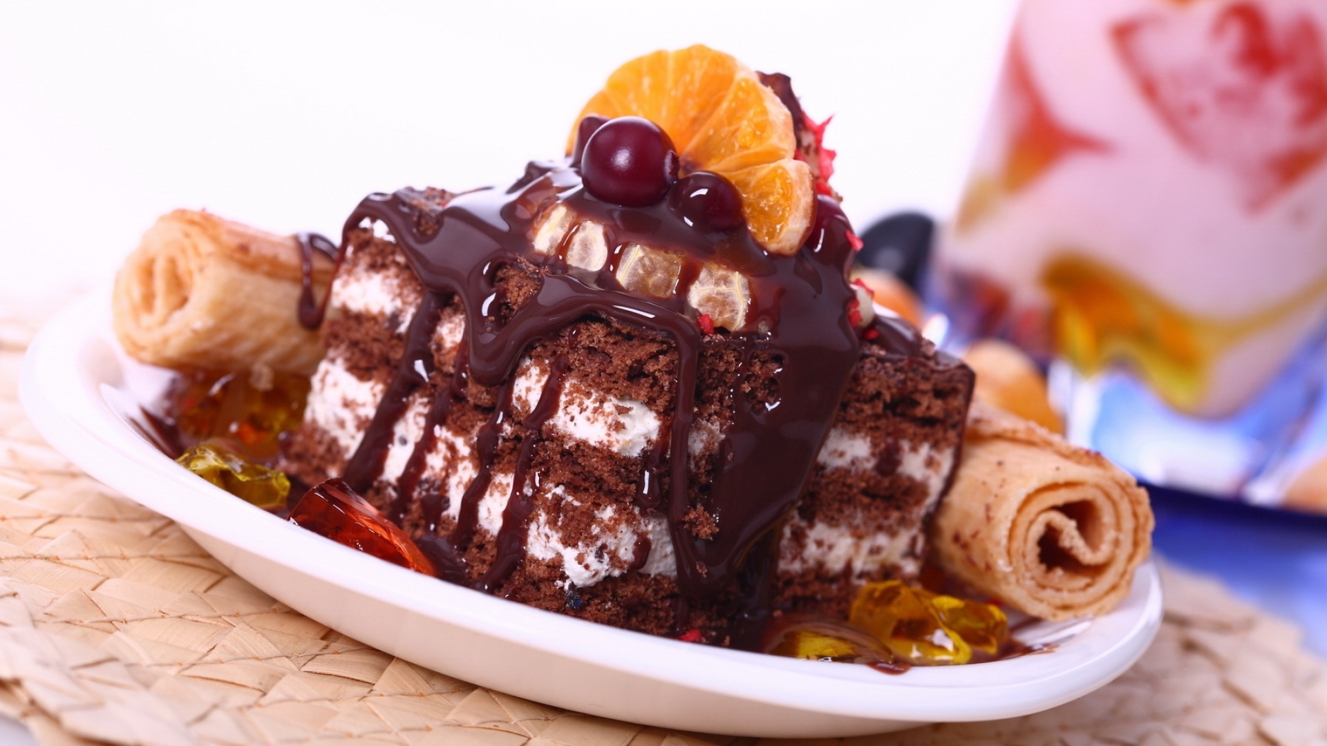 Аппетитное пирожное с шоколадной глазурью, трубочками и мандаринами