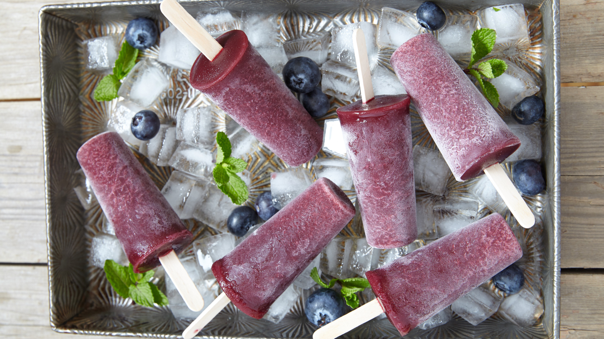 Вкусное черничное мороженое на палочке в лотке со льдом