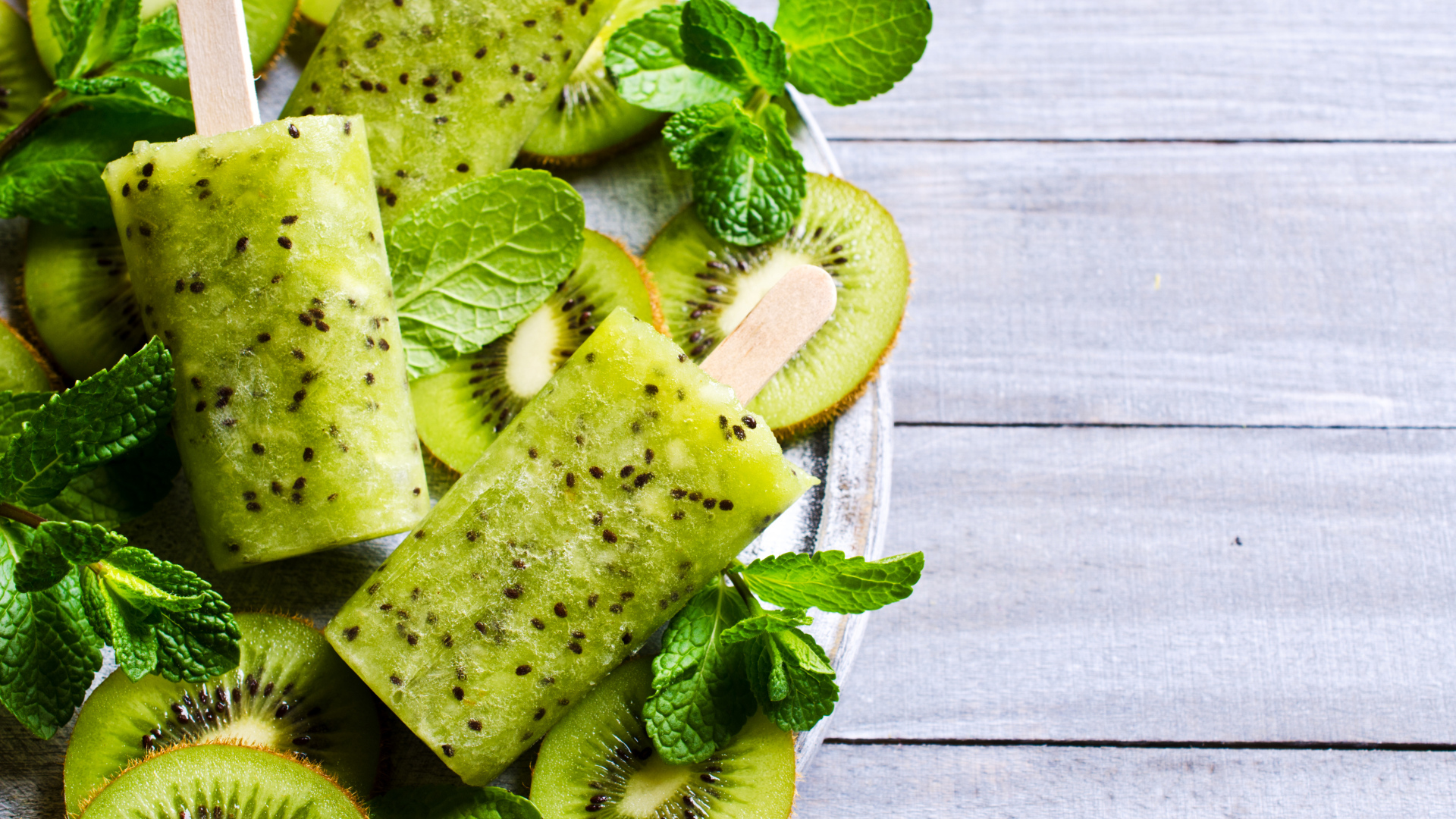 Мороженое с киви и листиками мяты на деревянном столе