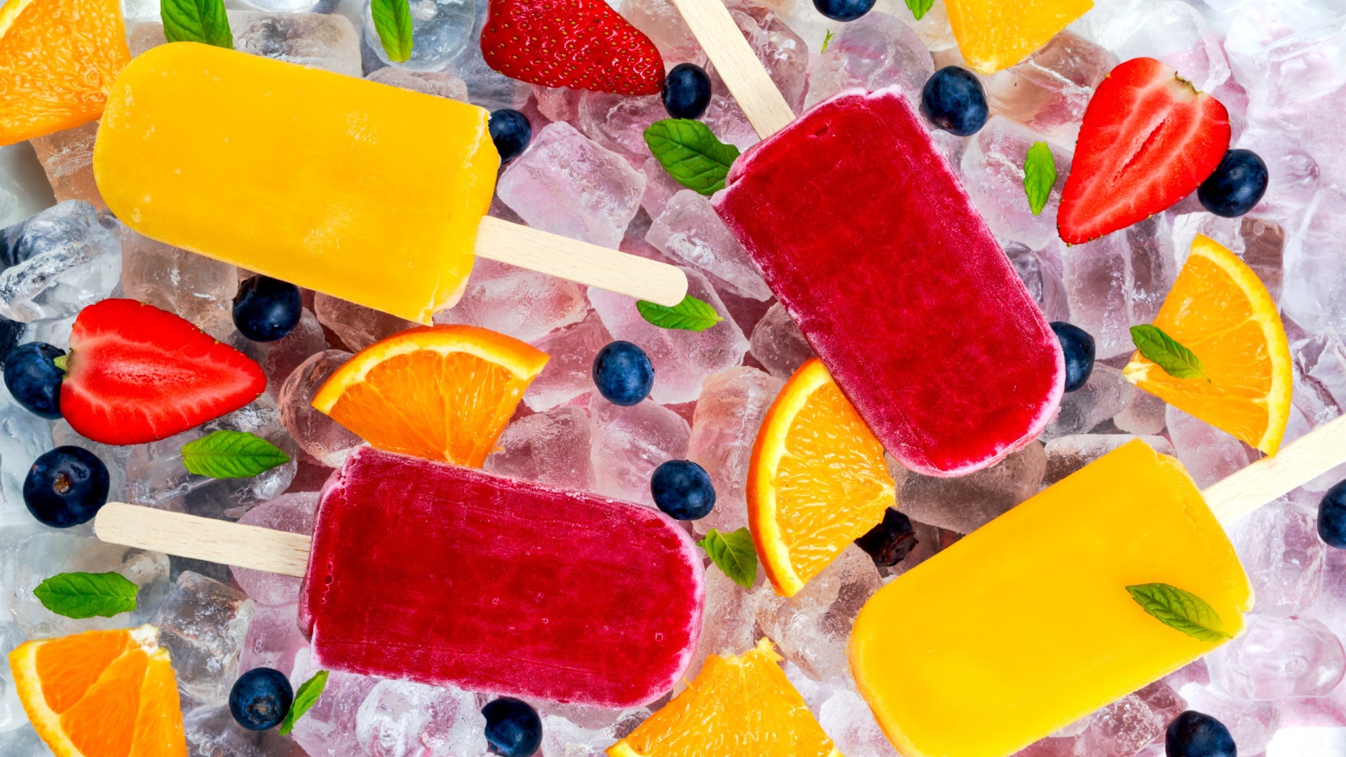Разноцветное фруктовое мороженое с ягодами лежит на кусочках льда