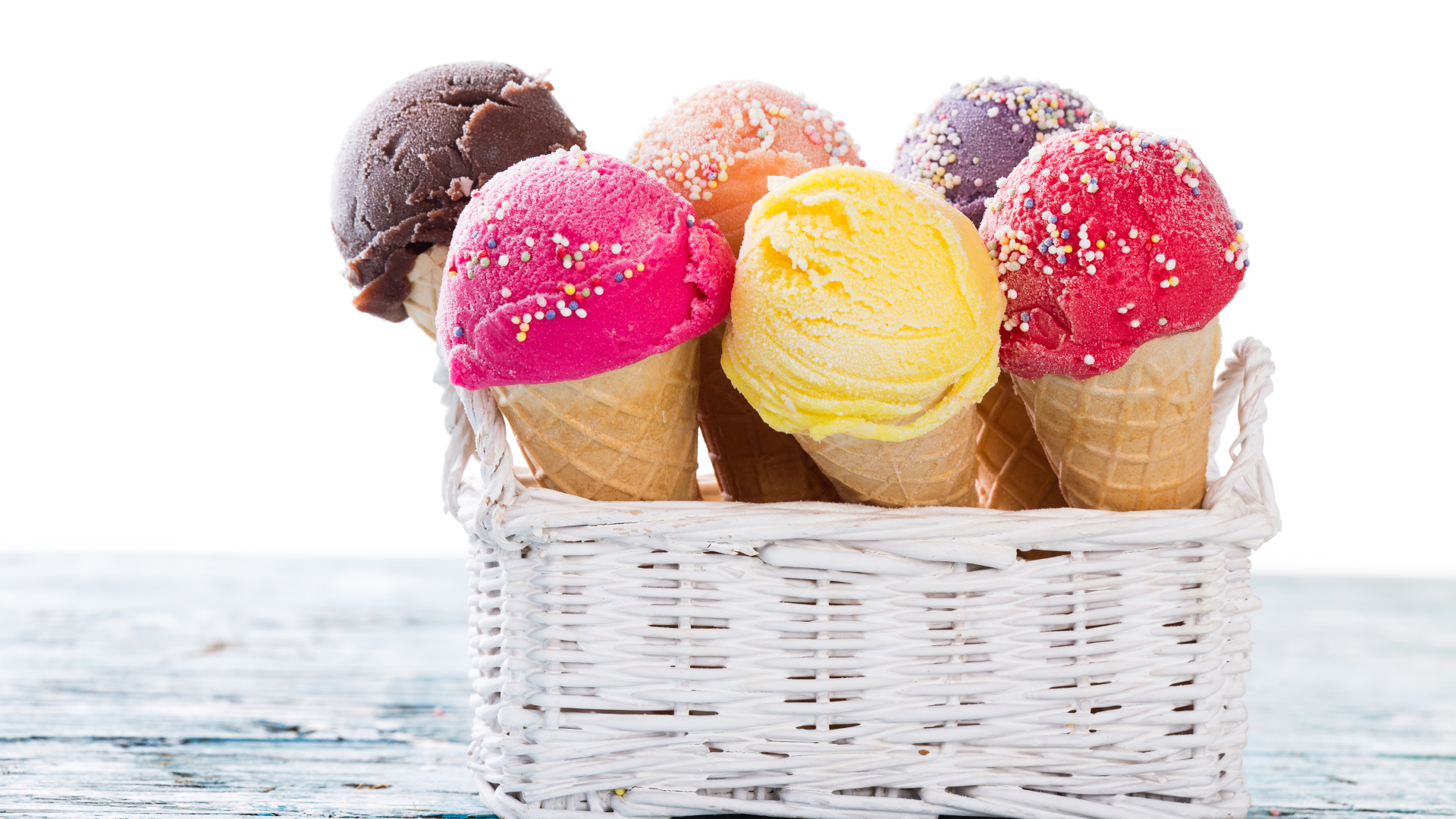 Разноцветное мороженое в вафельных рожках в белой корзине на столе