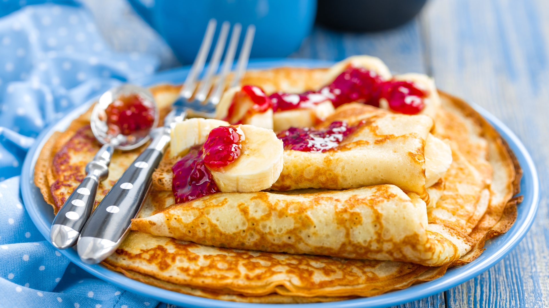 Блины с клубничным джемом и бананами на блюде 