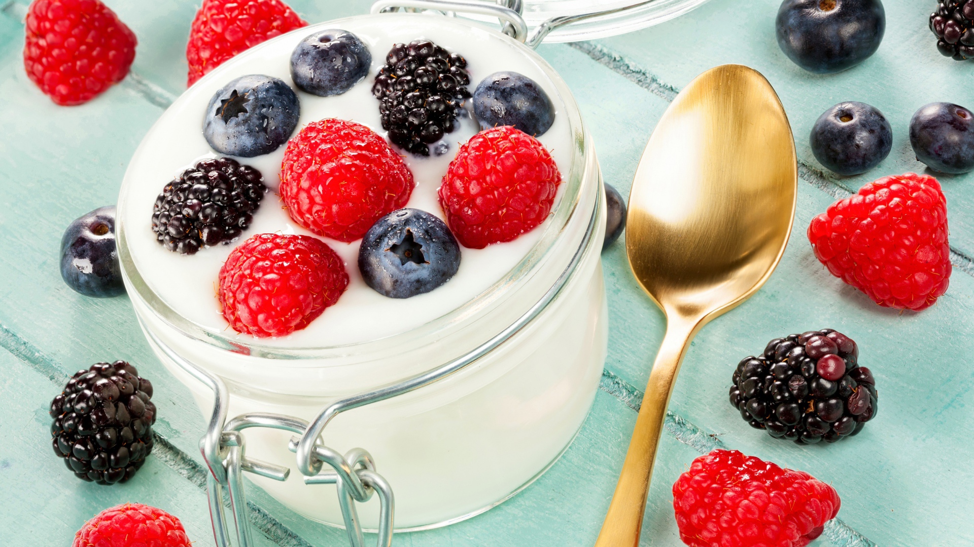 Йогурт со свежими ягодами малины, черники и ежевики в стеклянной банке на завтрак