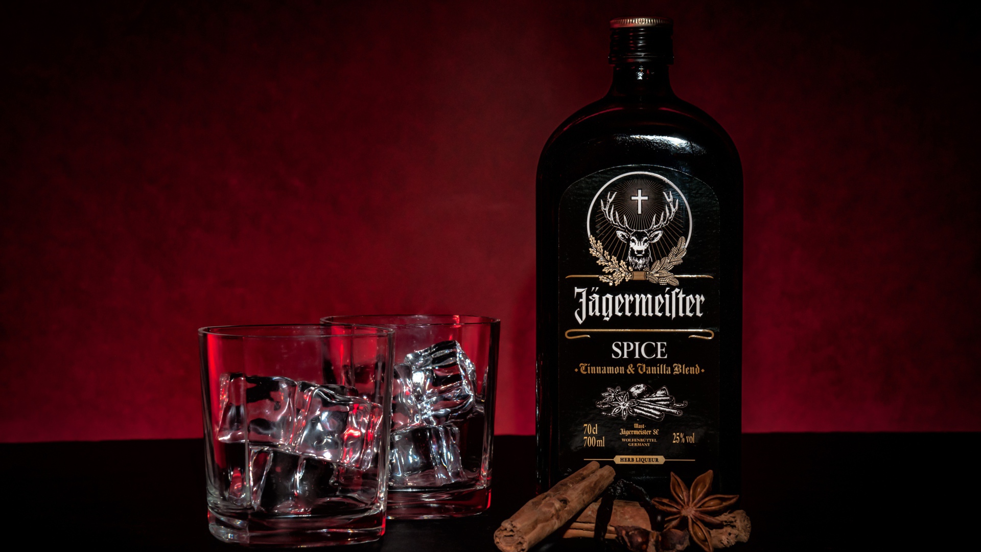 Бутылка ликера Jägermeister на столе с корицей и стаканами