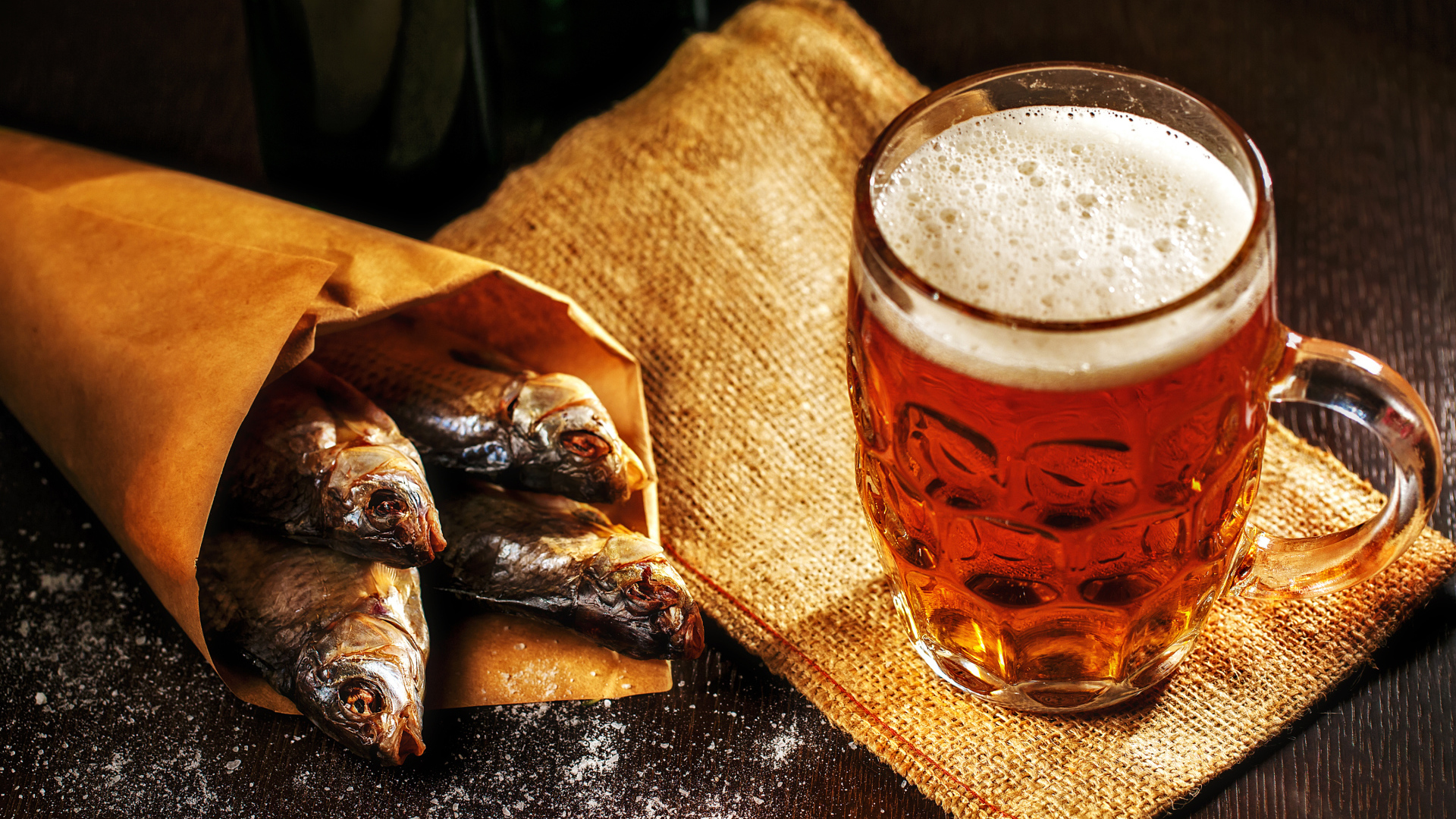 Бокал пива с сушеной рыбой на столе