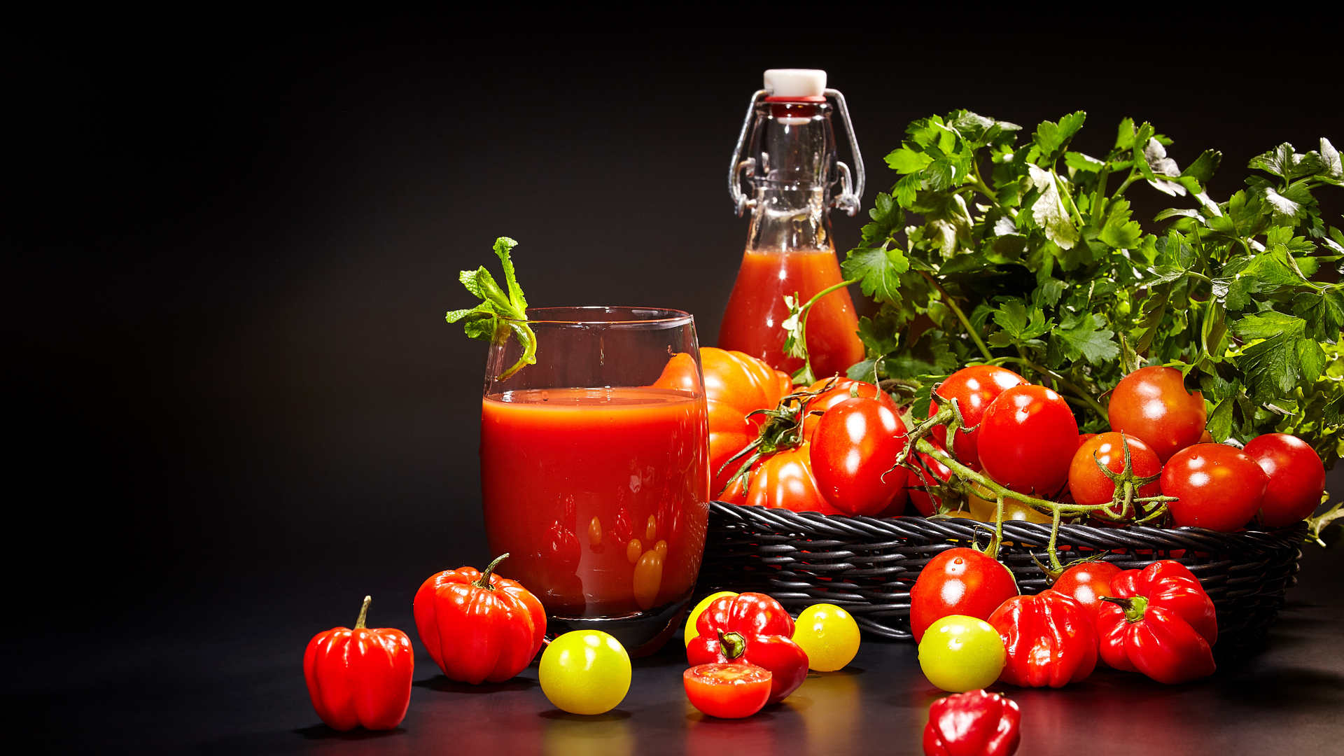 Томатный сок и свежие помидоры на столе на черном фоне