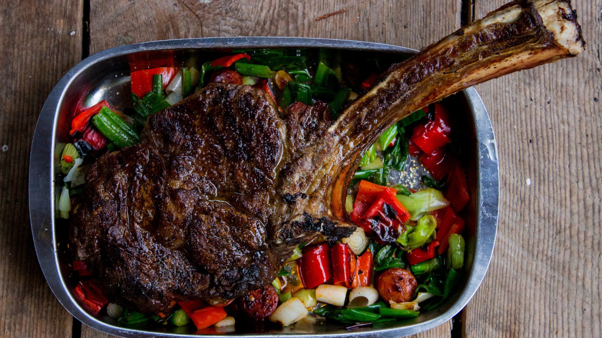 Кусок жареного мяса на ребрышке с овощами