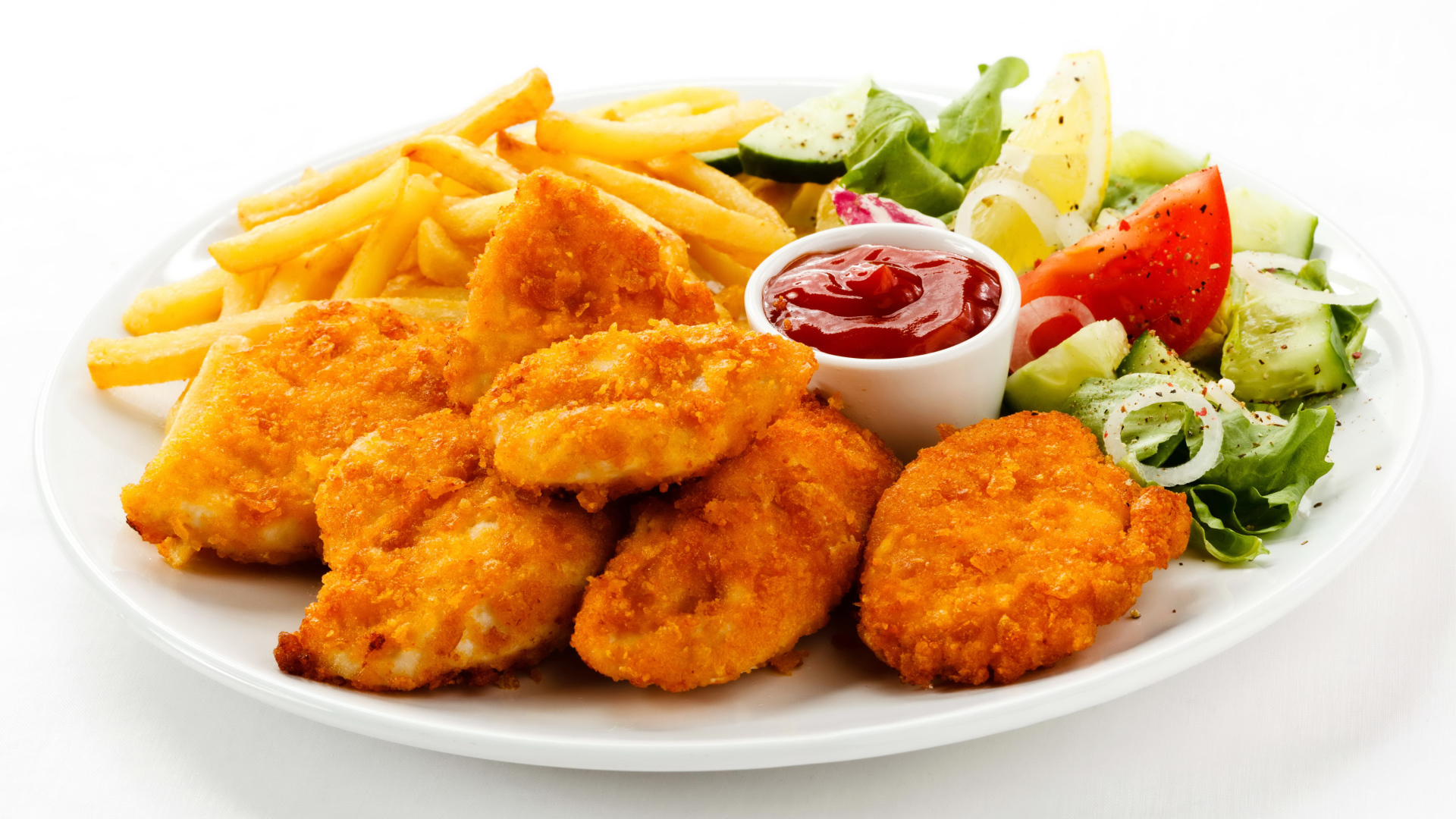 Куриные наггетсы с кетчупом, картофелем фри и салатом на белой тарелке