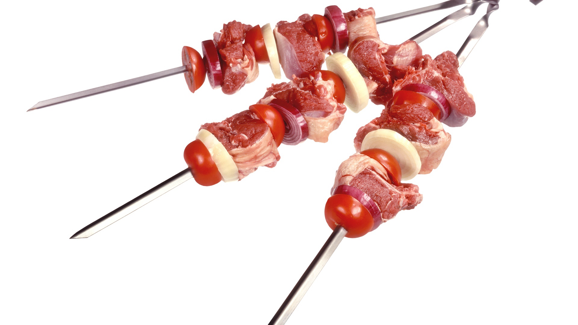 Мясо с овощами для шашлыка на шампурах на белом фоне