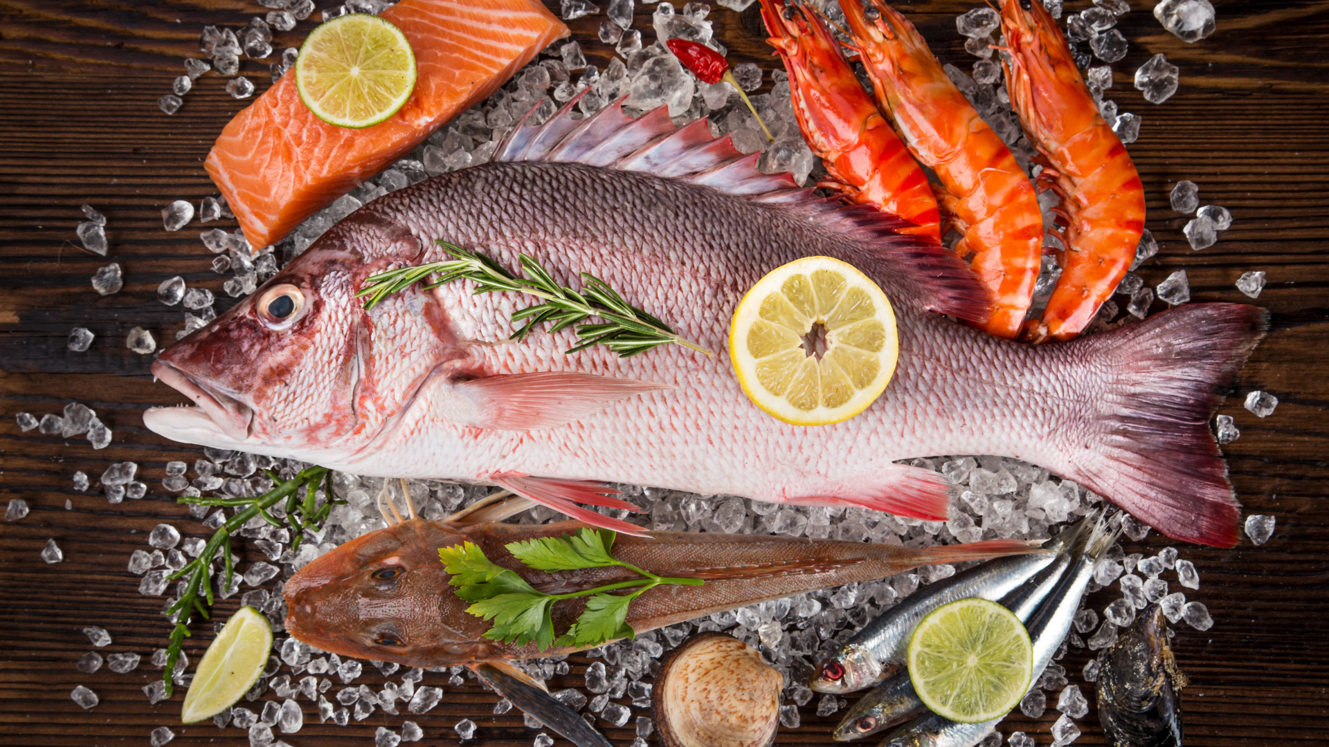 Свежая рыба с креветками и кусочками лимона лежит на кусочках льда