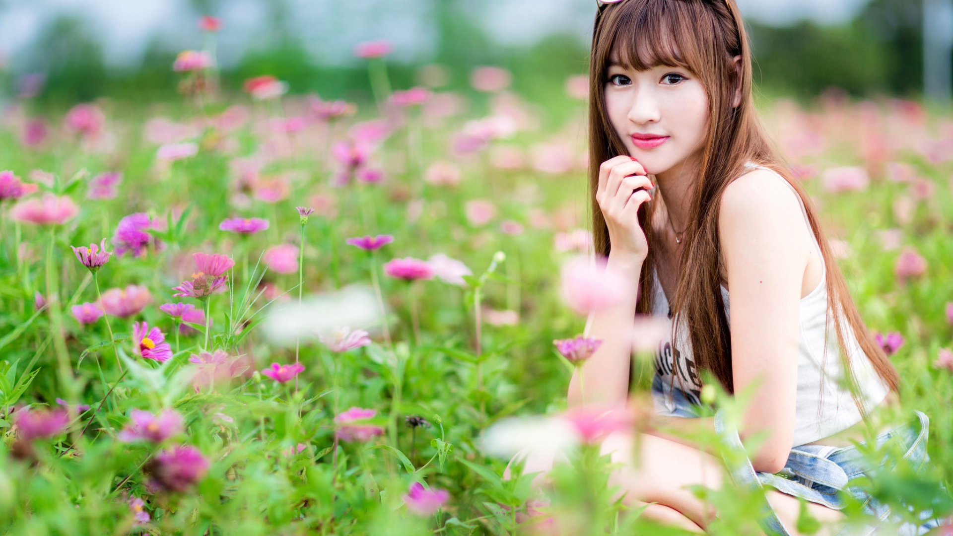 Красивая девушка модель азиатка на поле с розовыми цветами