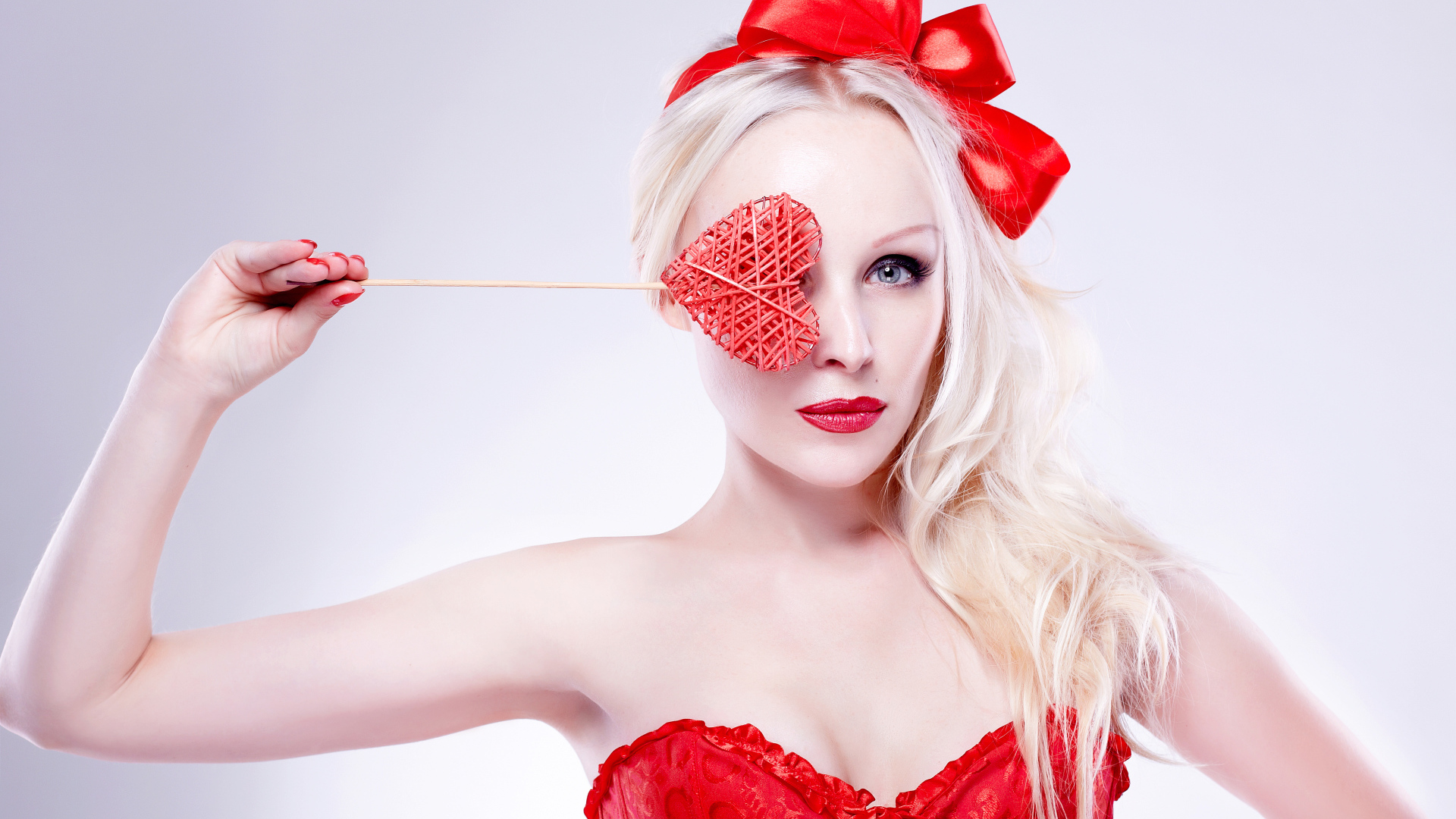 Красивая девушка блондинка в красном наряде с сердечком в руке