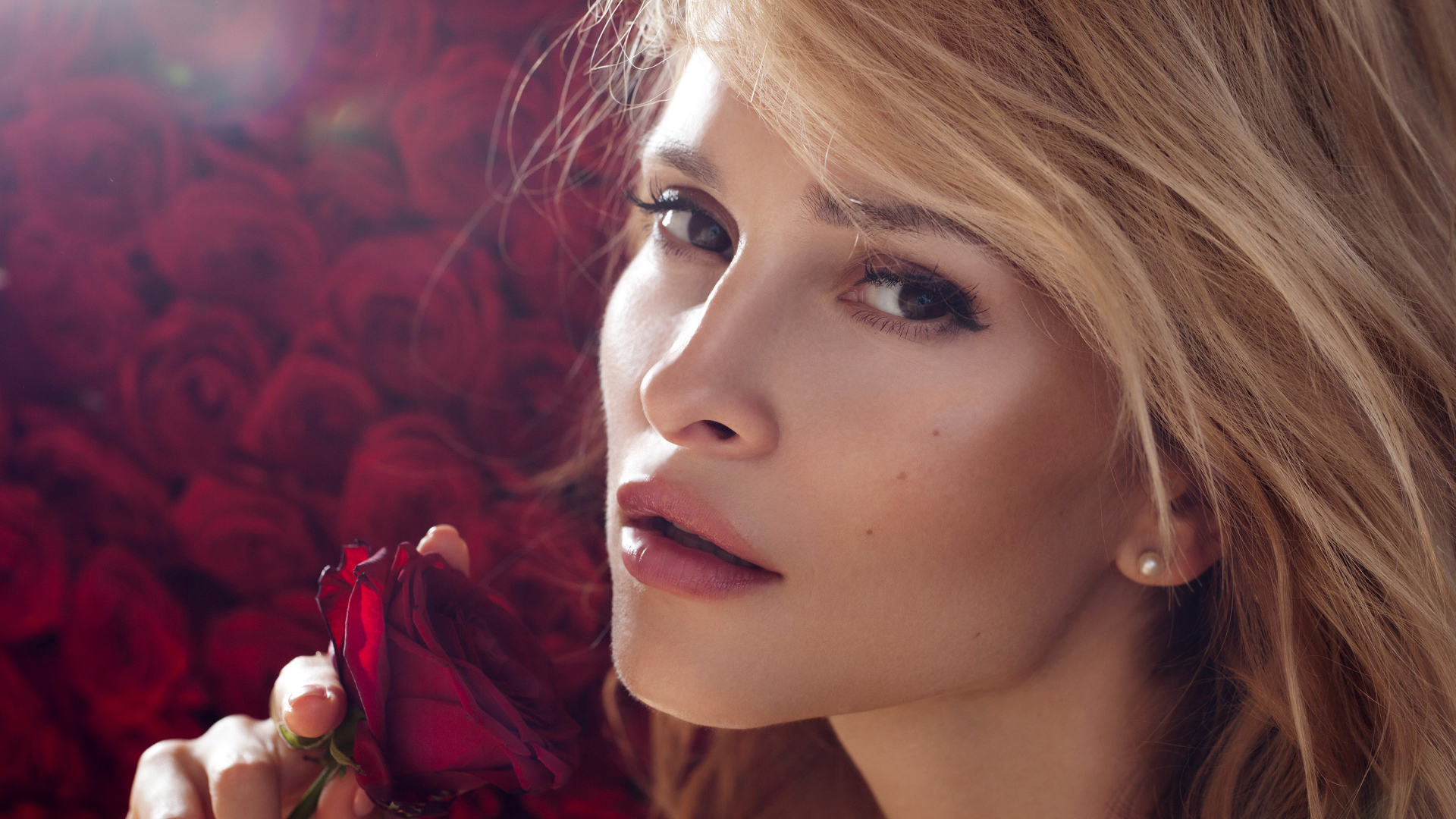 Красивая девушка блондинка с красной розой в руке