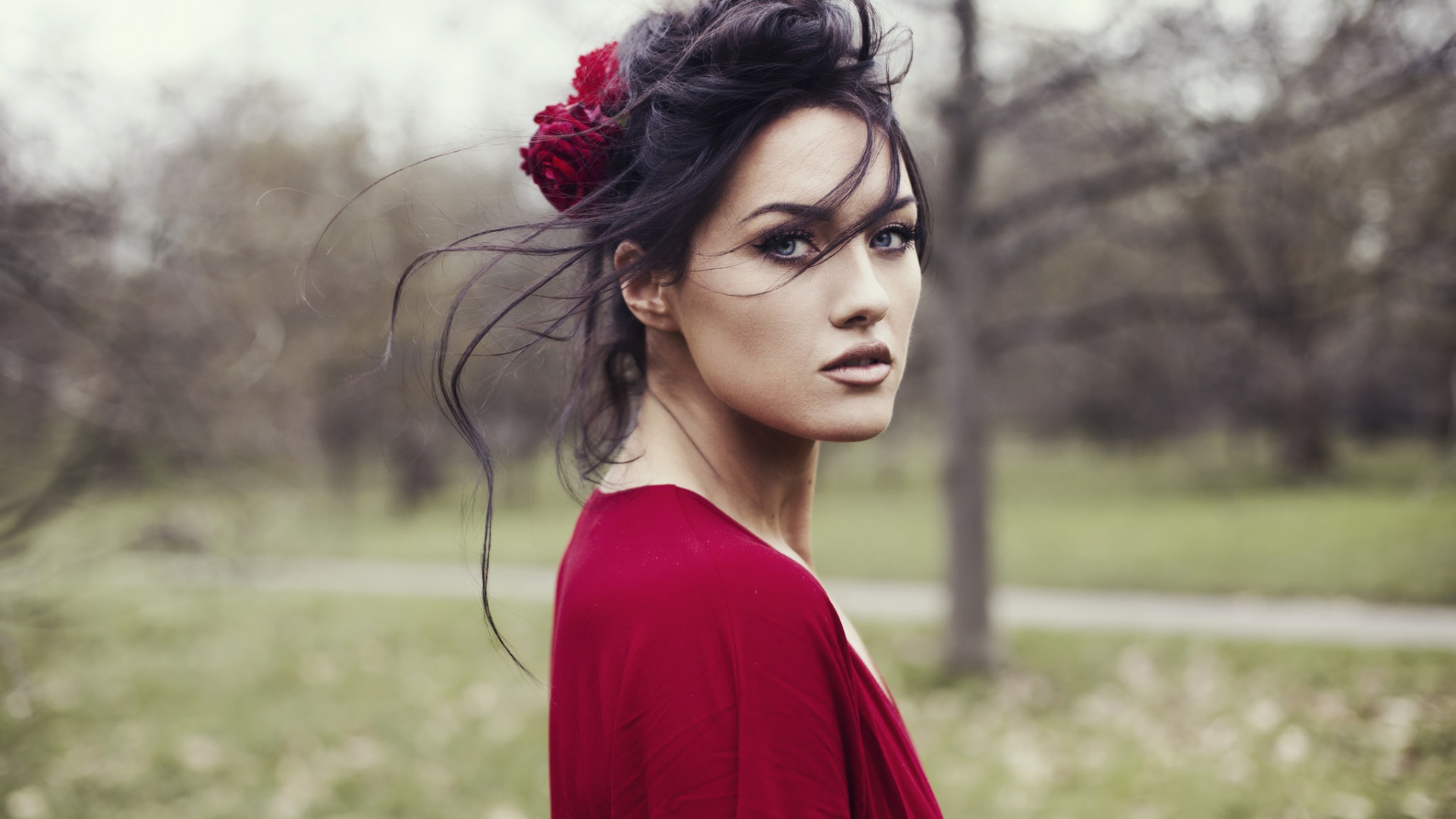Красивая брюнетка в красном платье с цветком в волосах