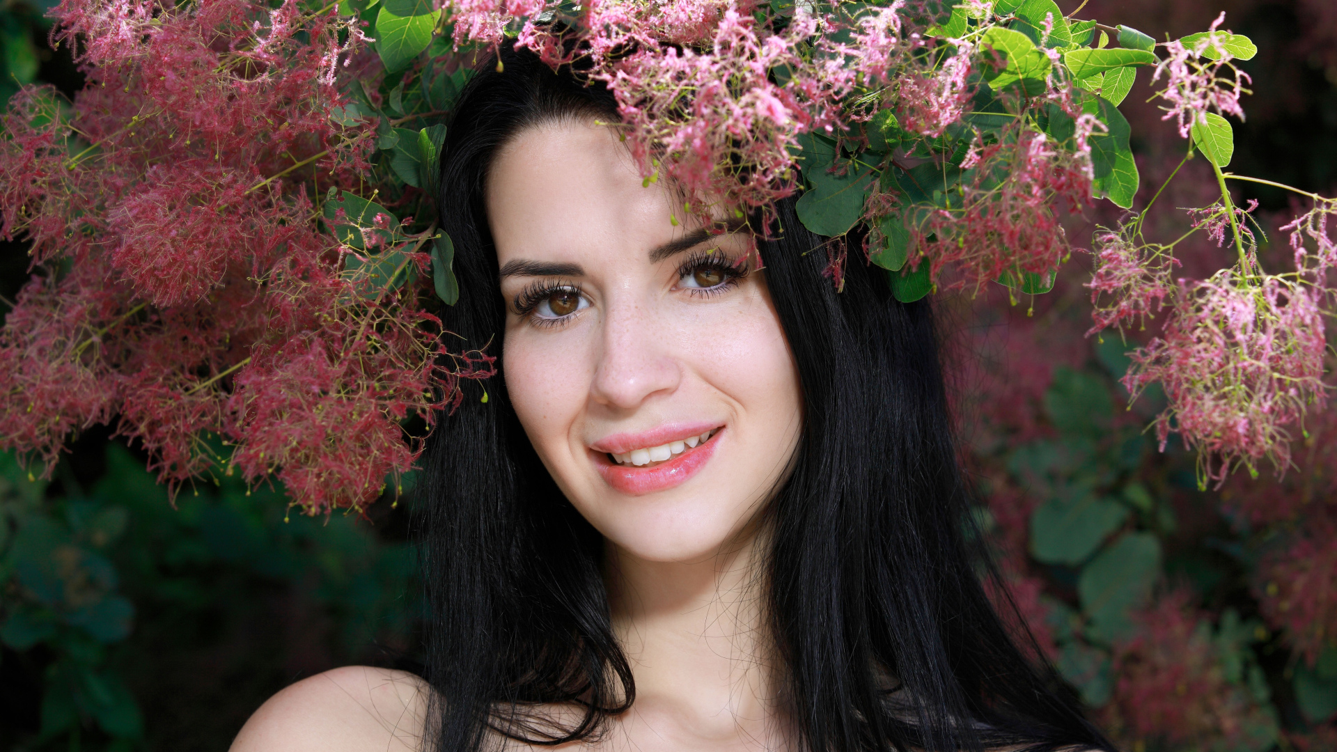 Красивая брюнетка стоит у цветущей ветки