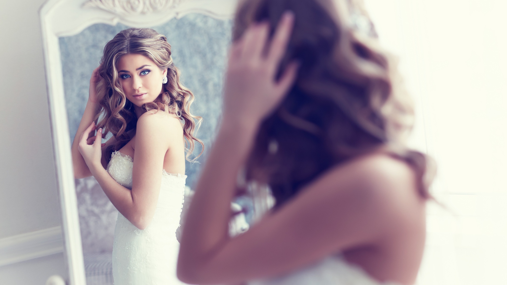 Красивая девушка в свадебном платье смотрит в зеркало 