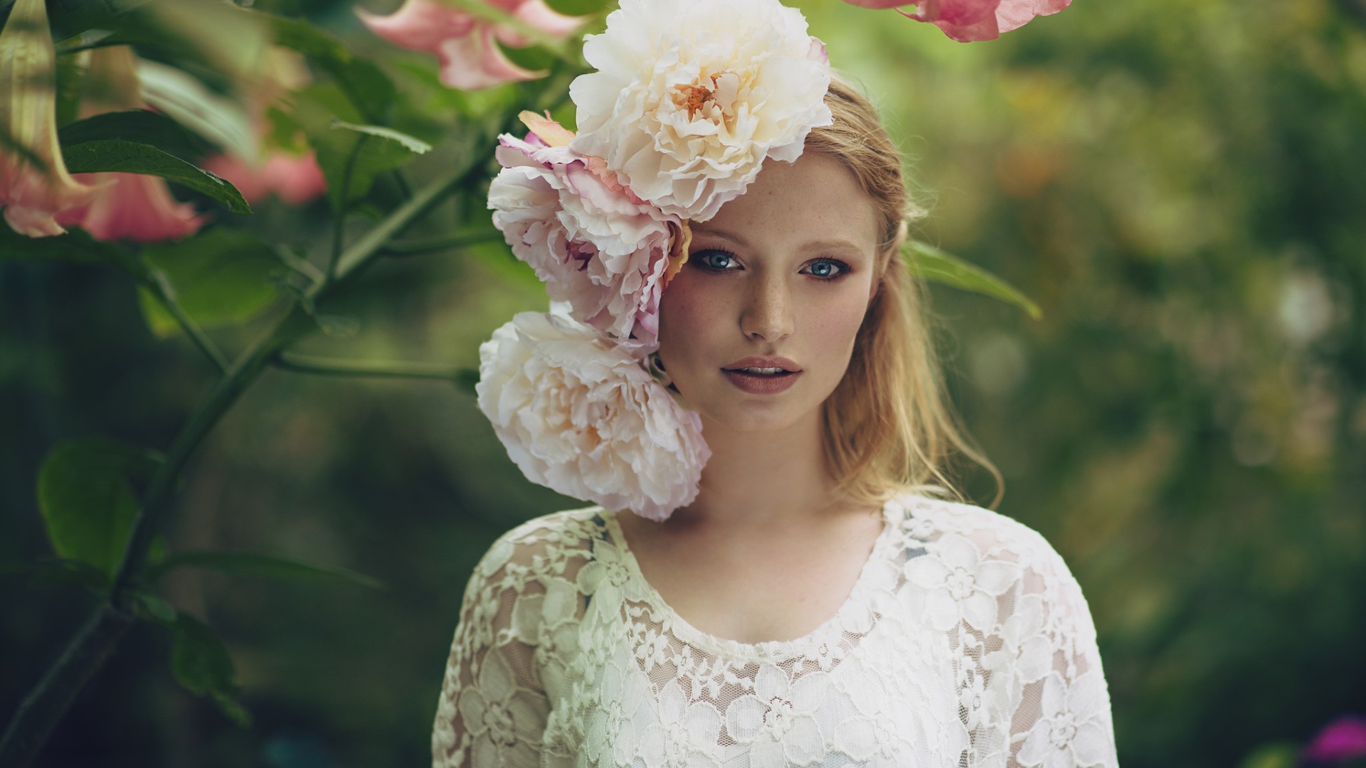 Красивая девушка в белом платье с большими пионами в волосах 