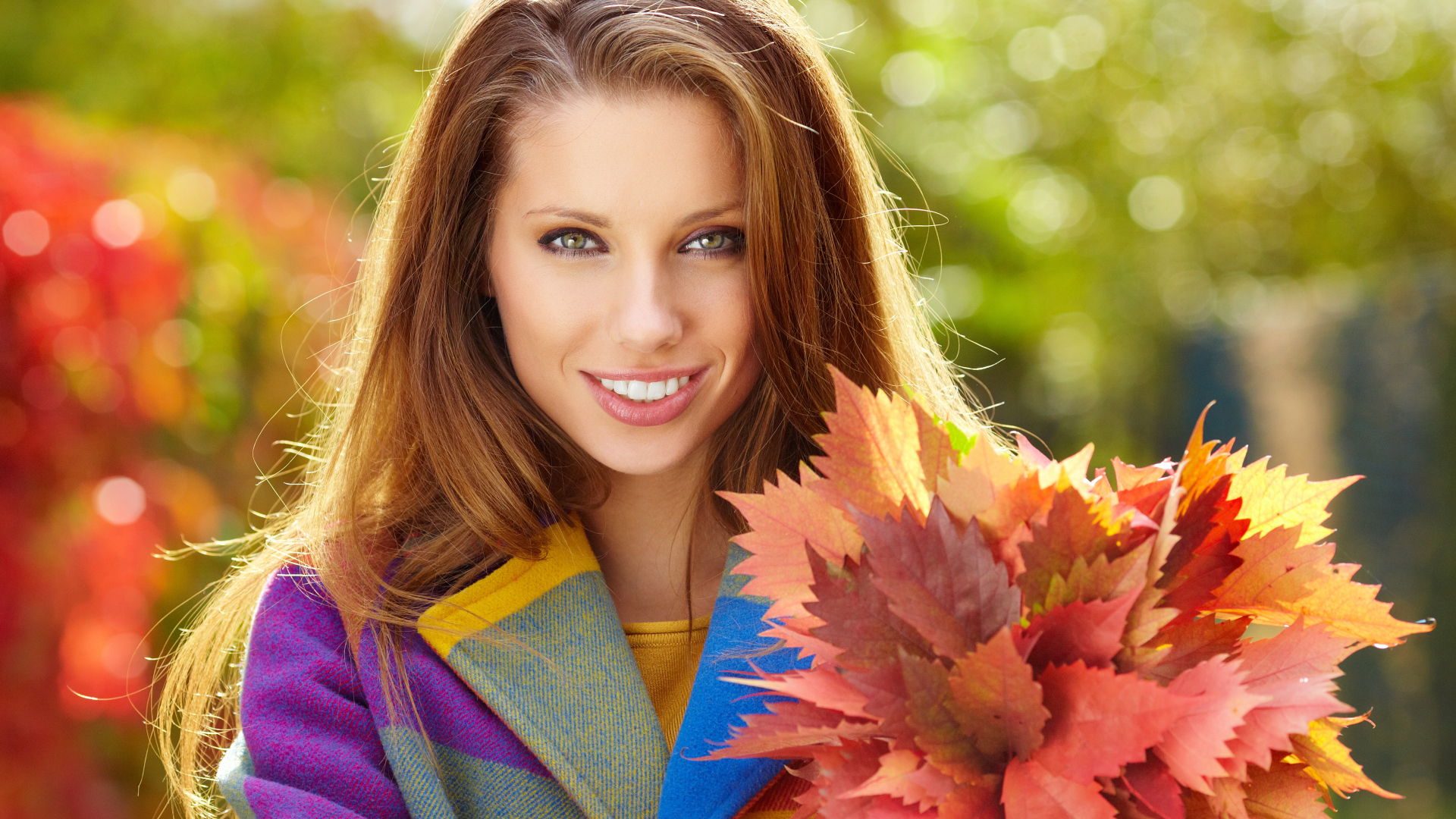 Красивая улыбающаяся девушка с букетом желтых листьев в руке