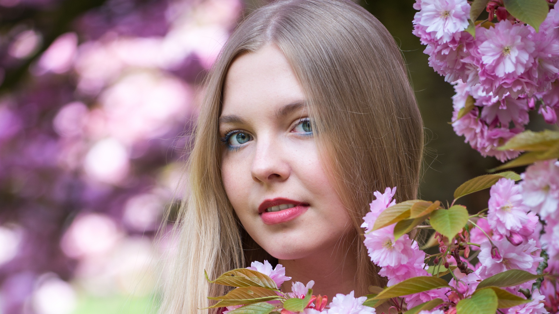 Милая голубоглазая девушка с розовыми цветами 