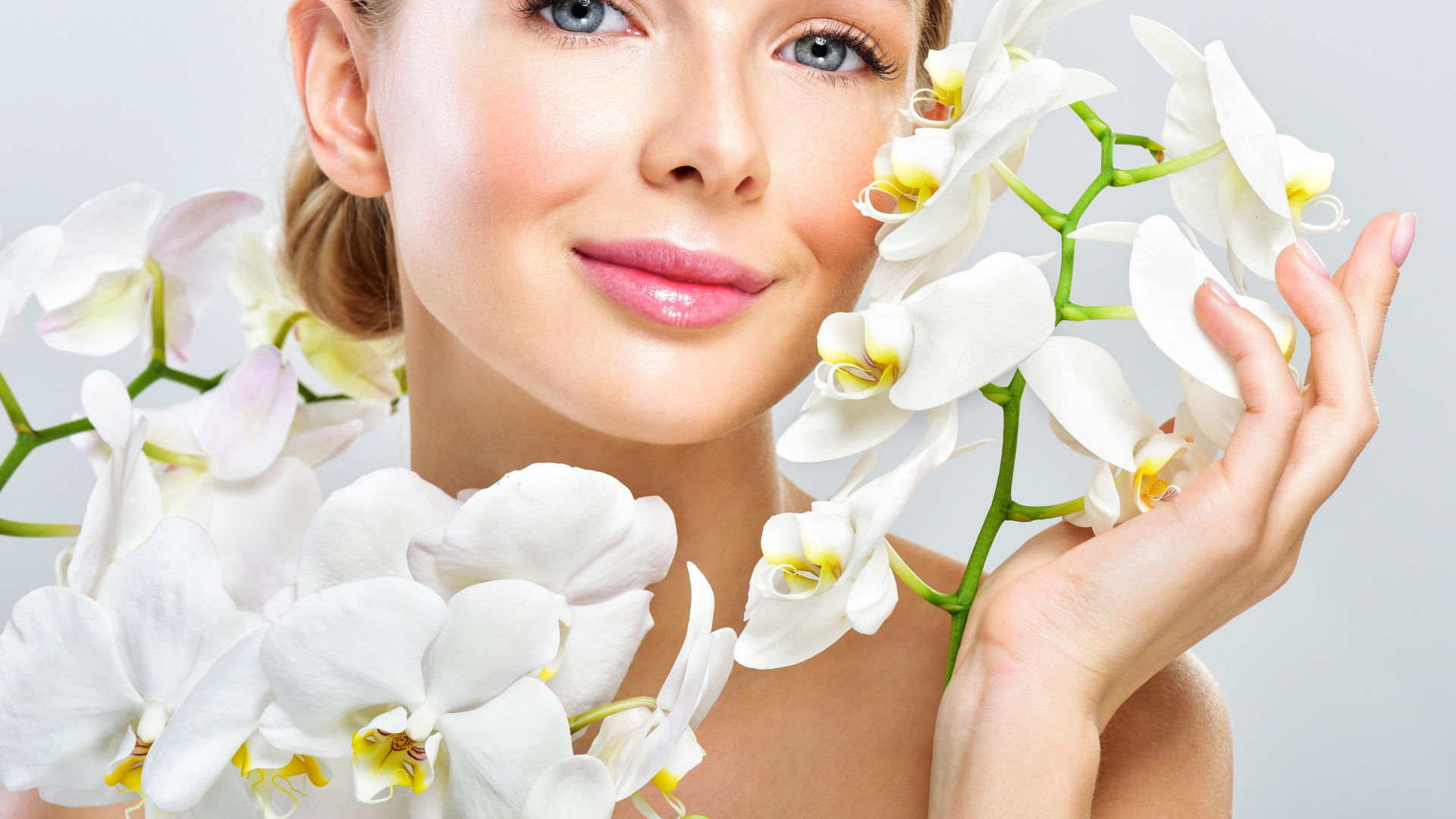 Нежная голубоглазая девушка с цветами орхидеи в руках