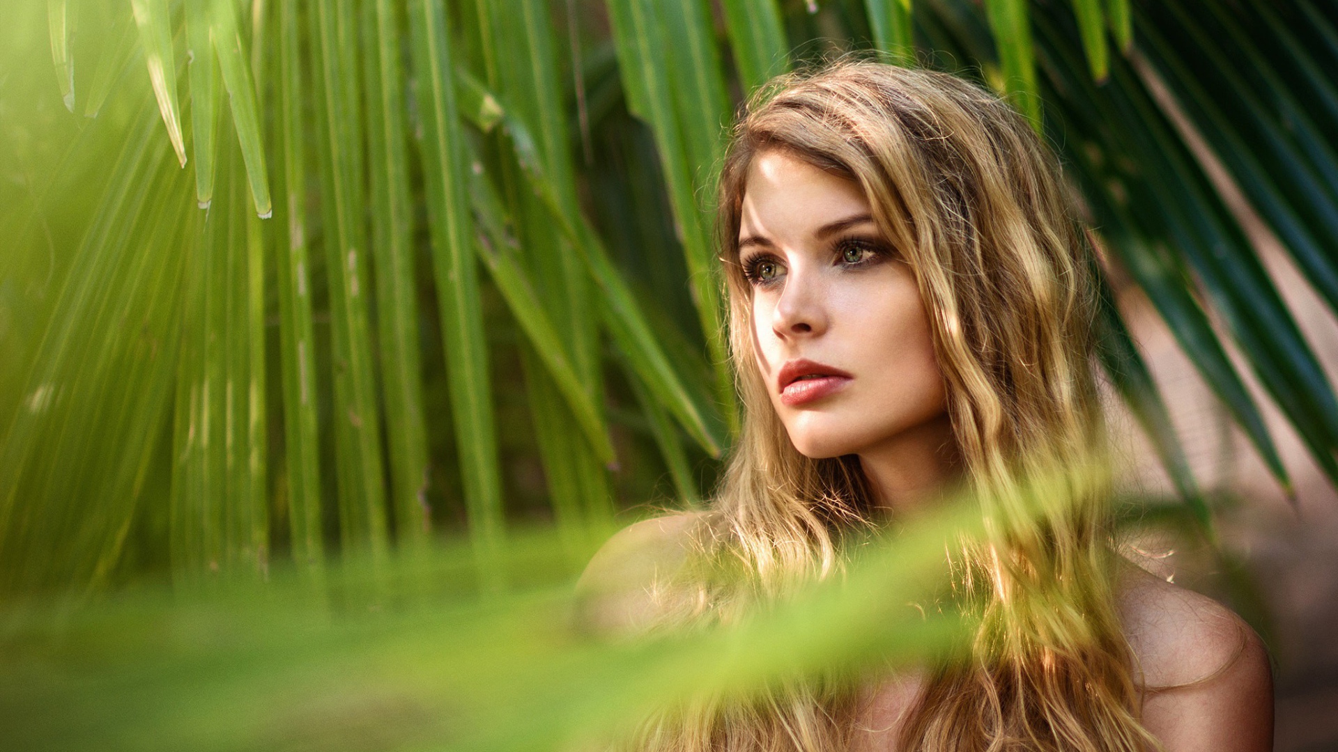 Девушка с волнистыми волосами в пальмовых листьях 