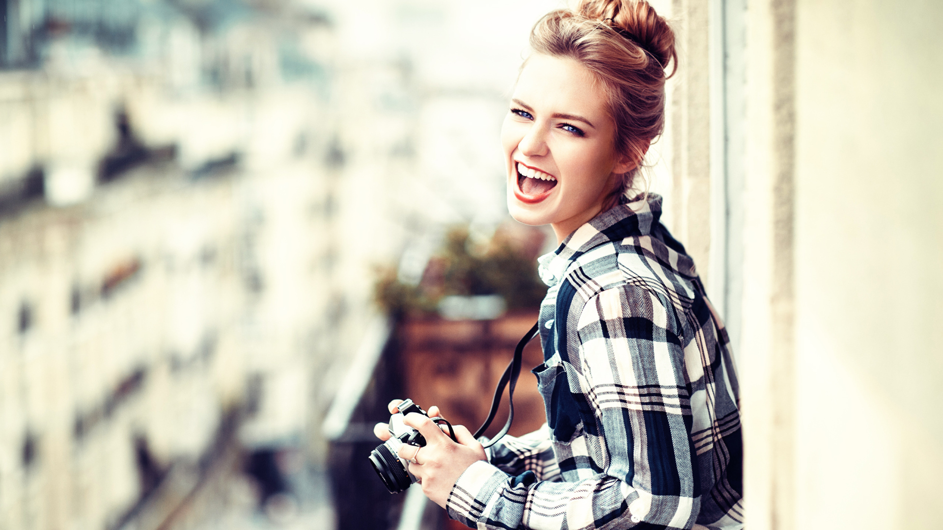 Улыбающаяся девушка в клетчатой рубашке с фотоаппаратом 