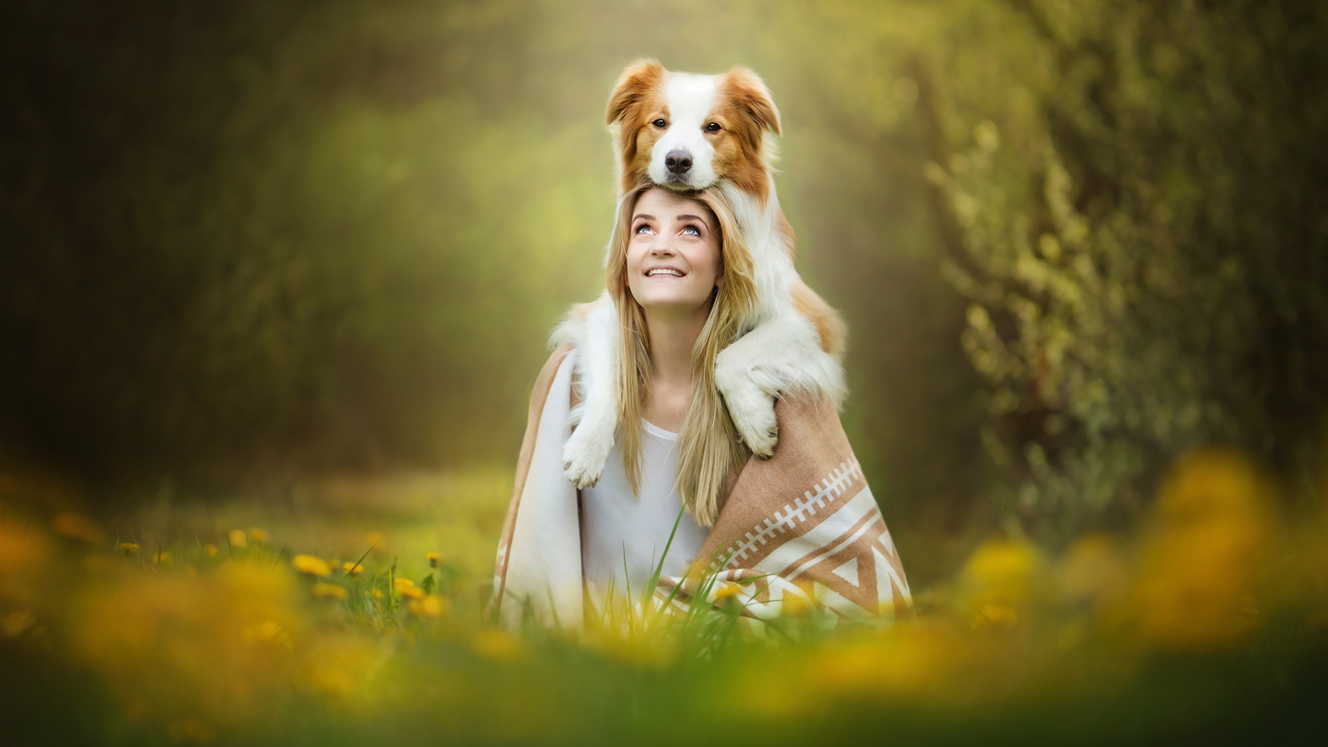 Улыбающаяся девушка с собакой сидят на траве