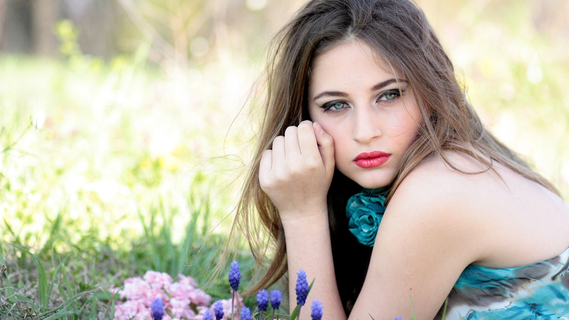 Молодая девушка брюнетка с голубыми глазами лежит на траве 