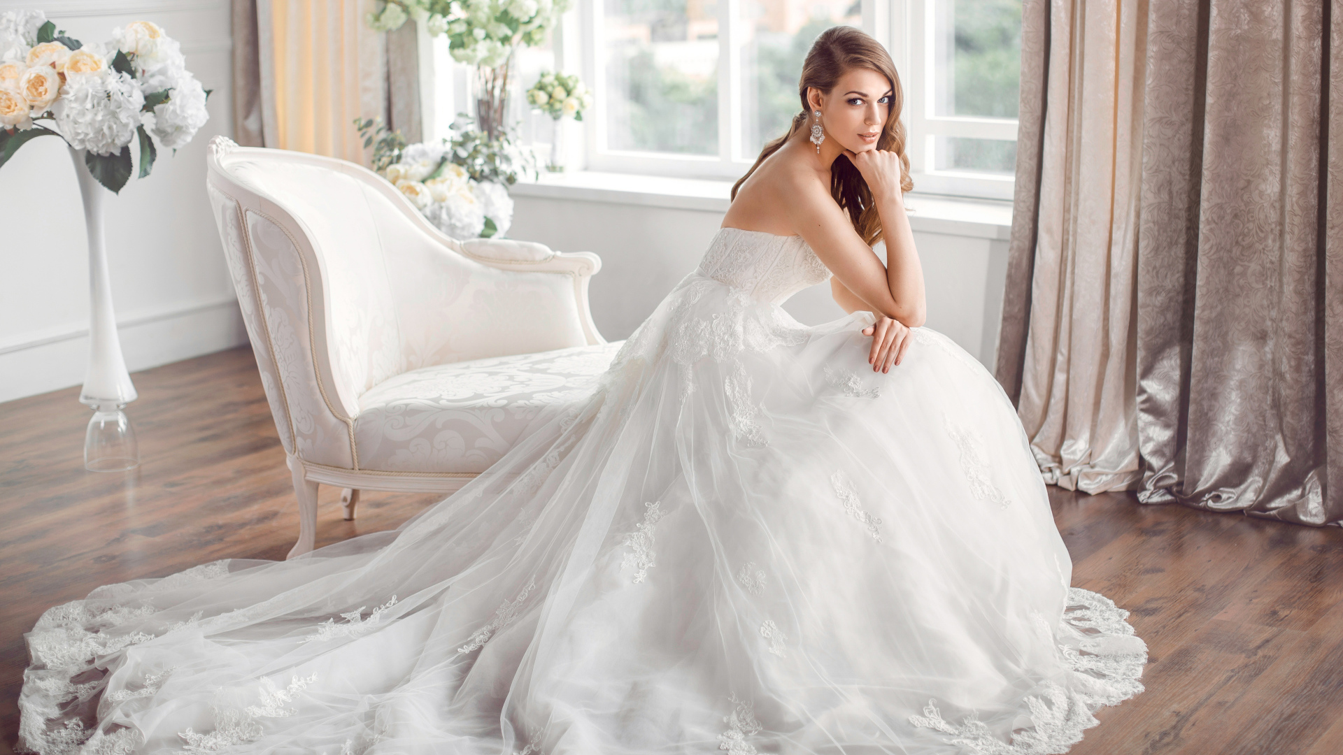 Молодая девушка в красивом свадебном платье сидит в белом кресле