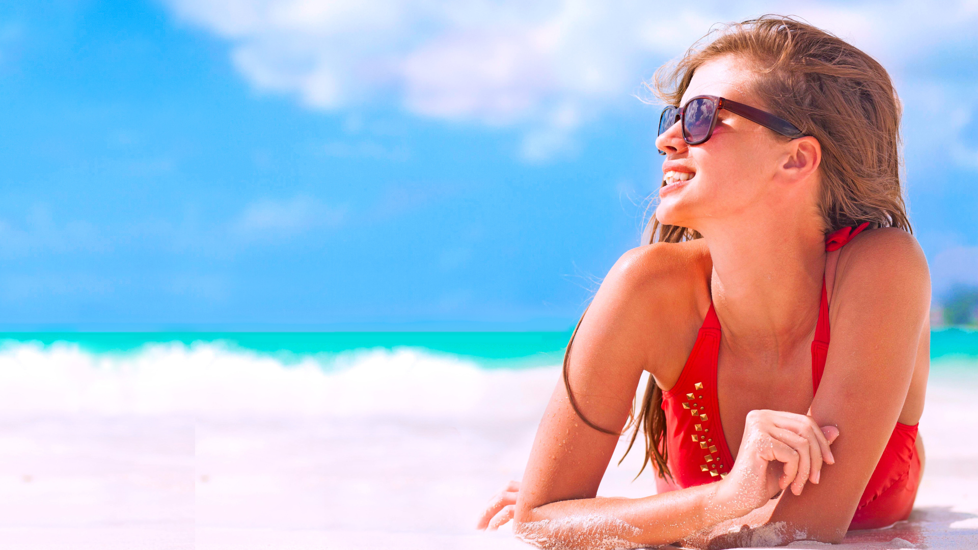 Молодая девушка в очках загорает на пляже