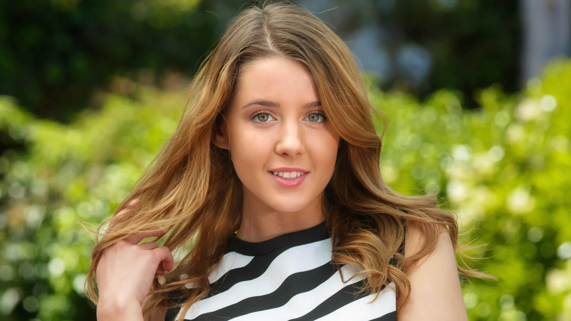 Молодая улыбающаяся девушка в полосатом платье