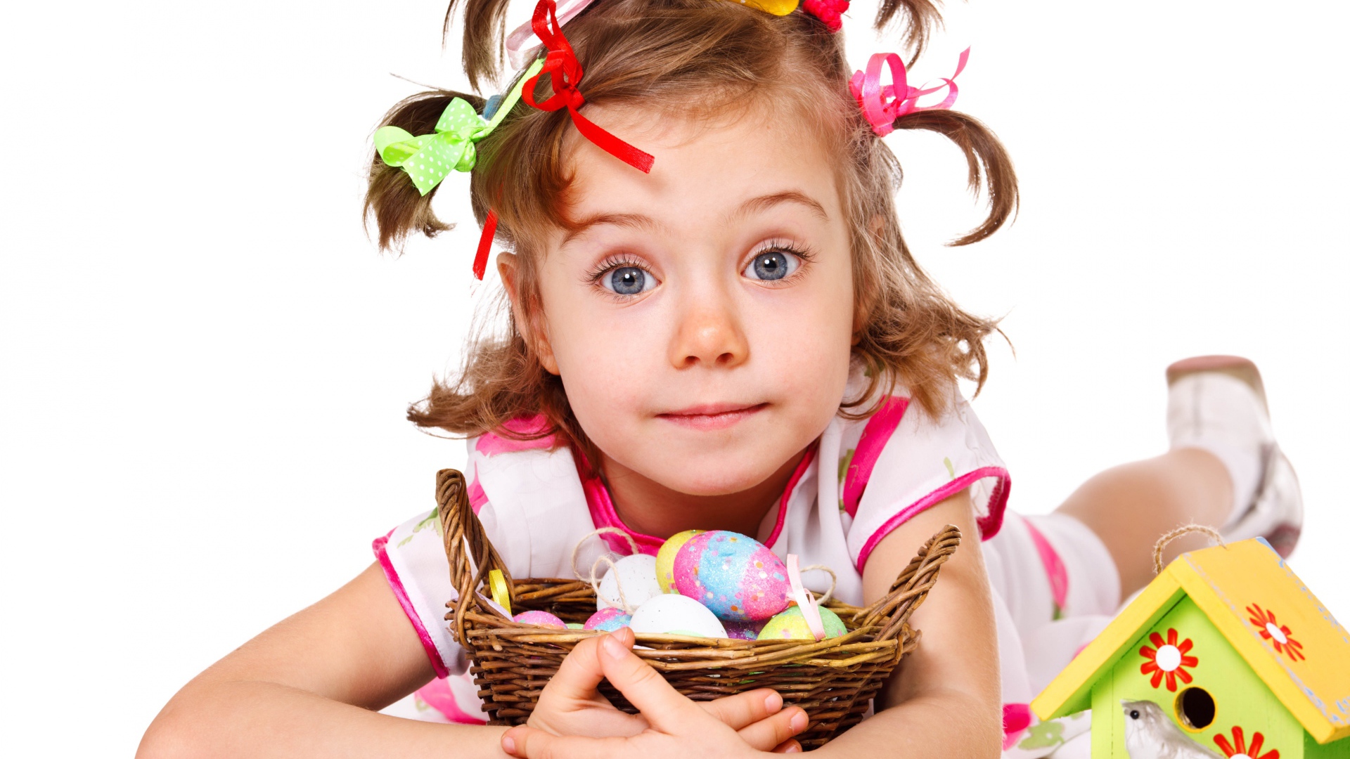 Маленькая девочка с корзинкой пасхальных яиц на белом фоне 
