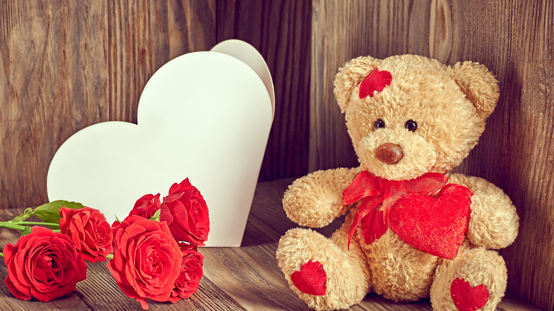 Плюшевый медведь с большим белым бумажным сердцем и красными розами
