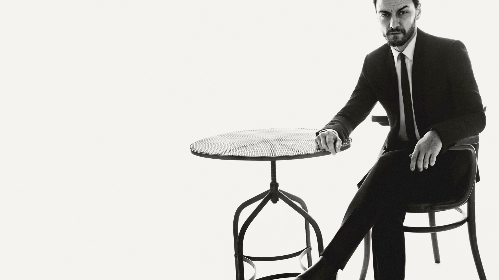 Актер Джеймс Макэвой сидит на стуле за столом черно-белое фото