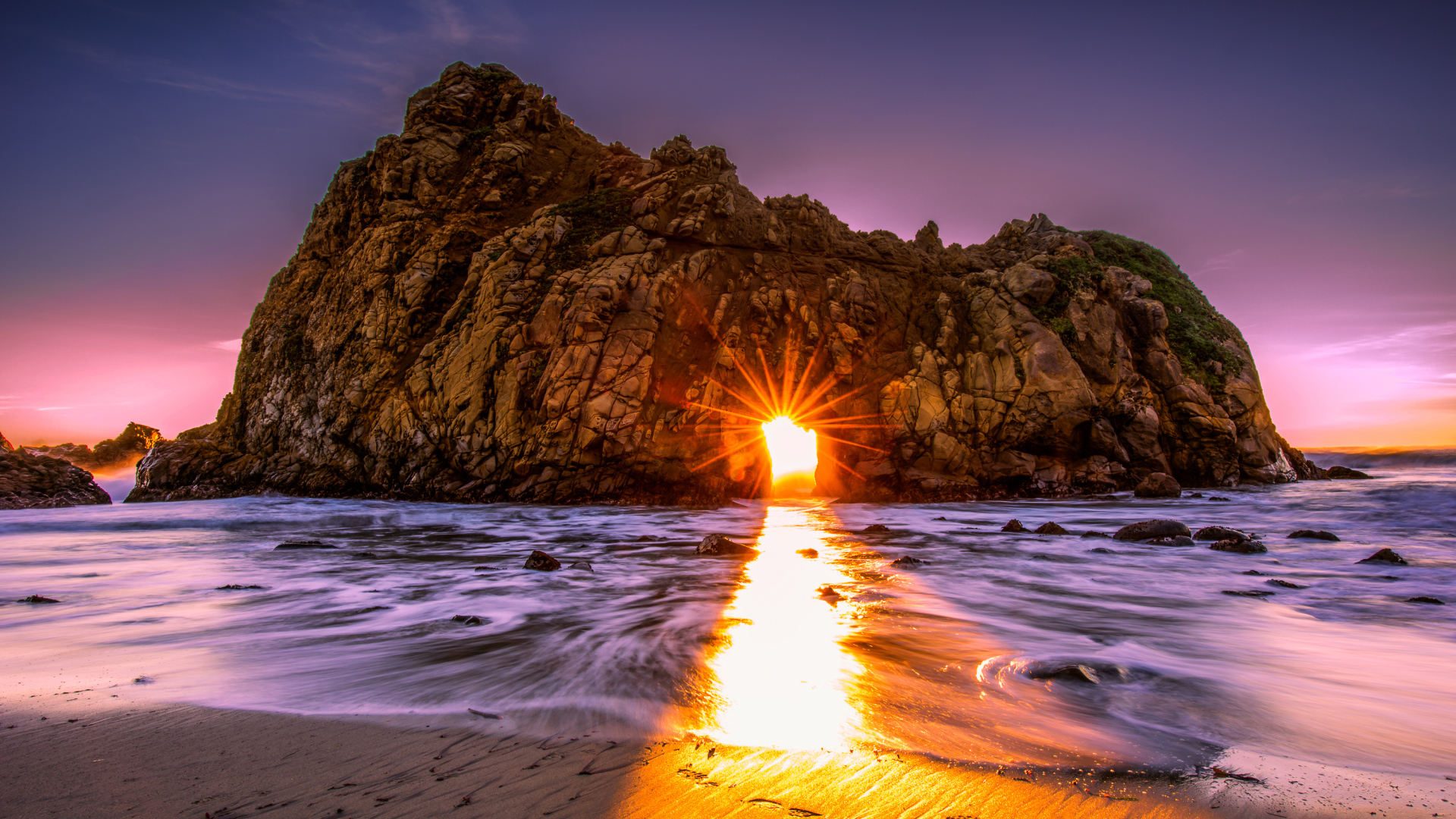 Лучи солнца пробиваются сквозь отверстие в скале  Pfeiffer Beach Big Sur, Калифорния  