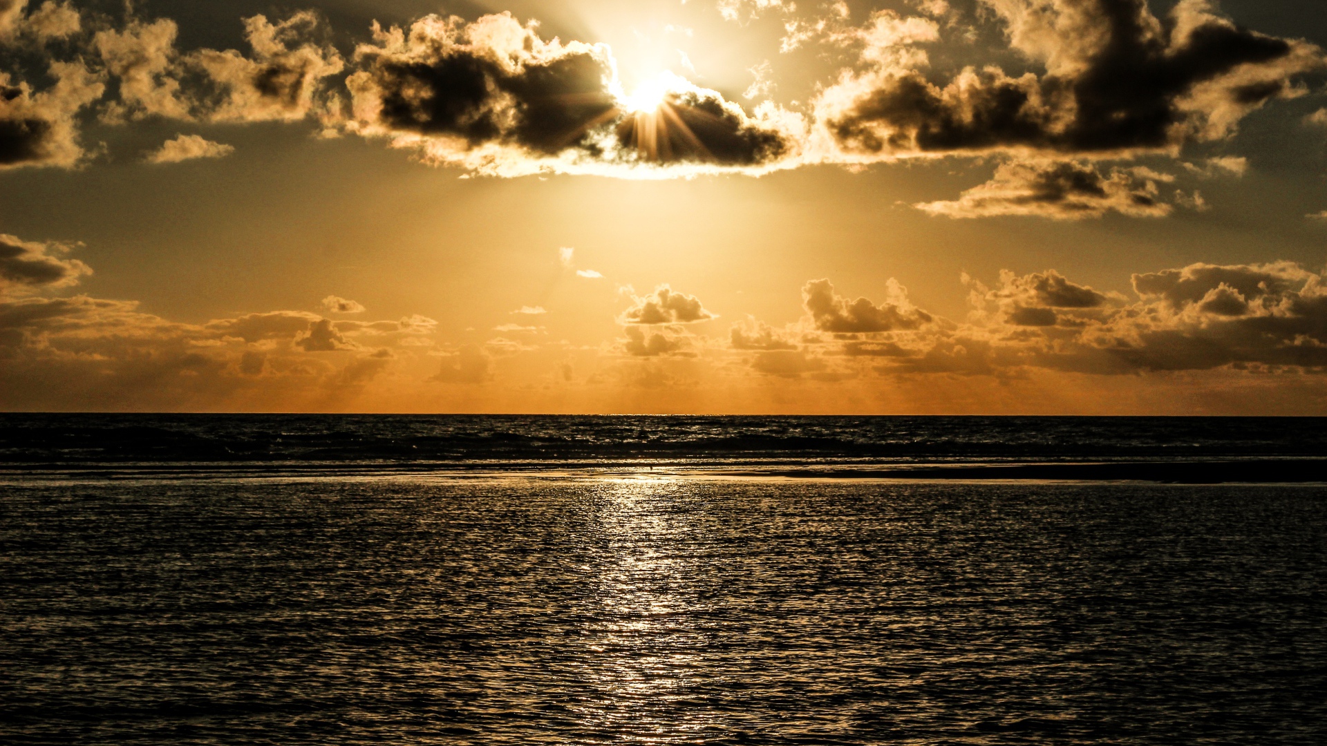 Солнечные лучи пробиваются сквозь облака над океаном