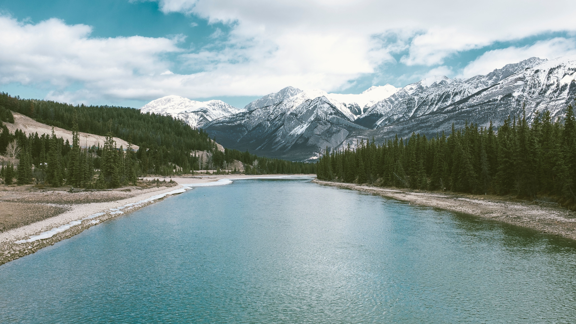 Чистая голубая вода в реке на фоне заснеженных гор 