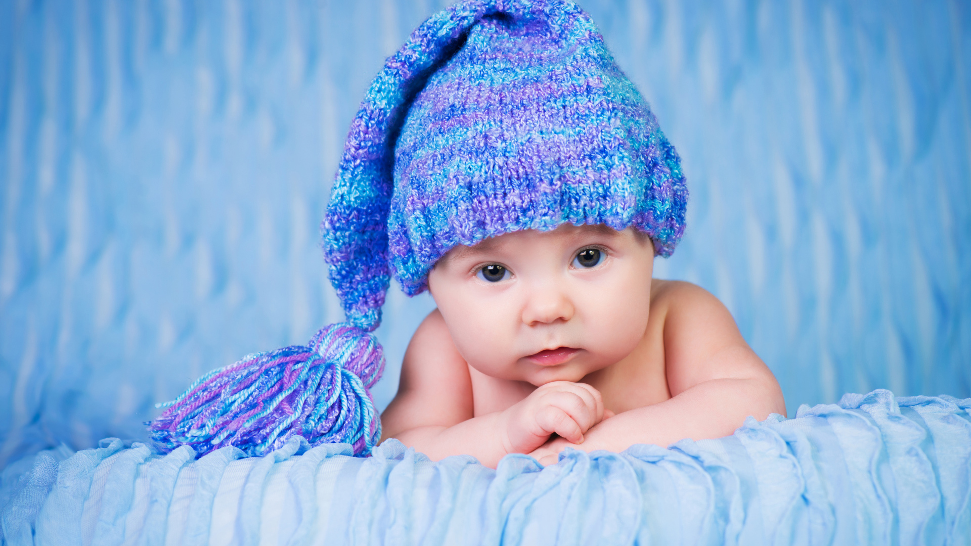 Грудной ребенок в красивой вязаной синей шапке