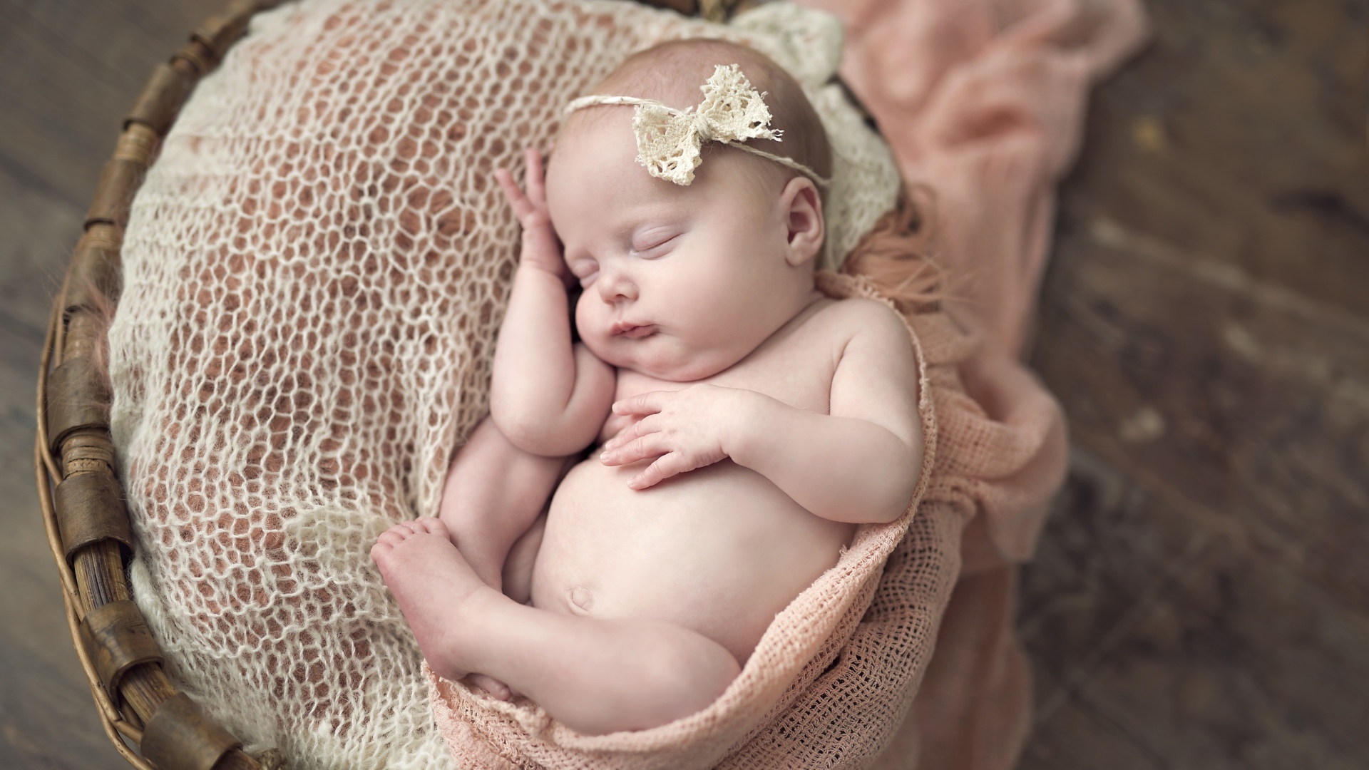 Грудной ребенок с бантиком на голове спит в корзине
