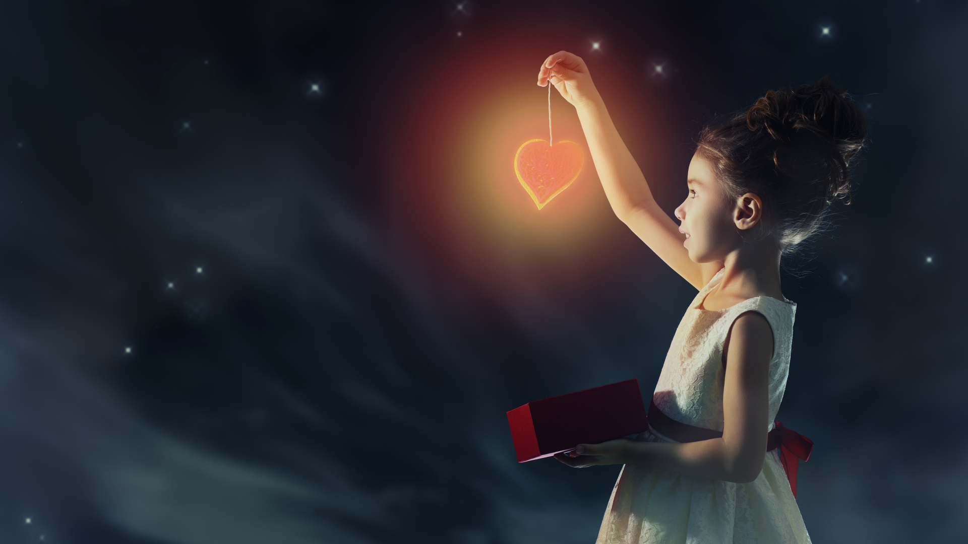 Девочка в красивом белом платье держит в руках сердечко