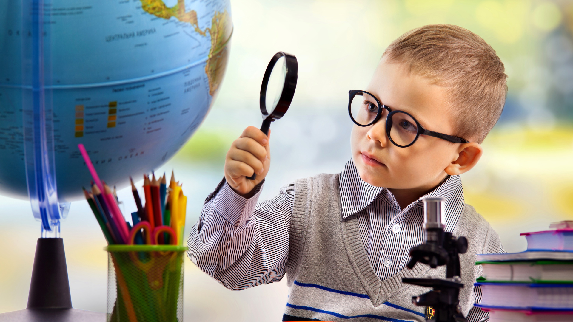 Маленький мальчик в очках исследует глобус