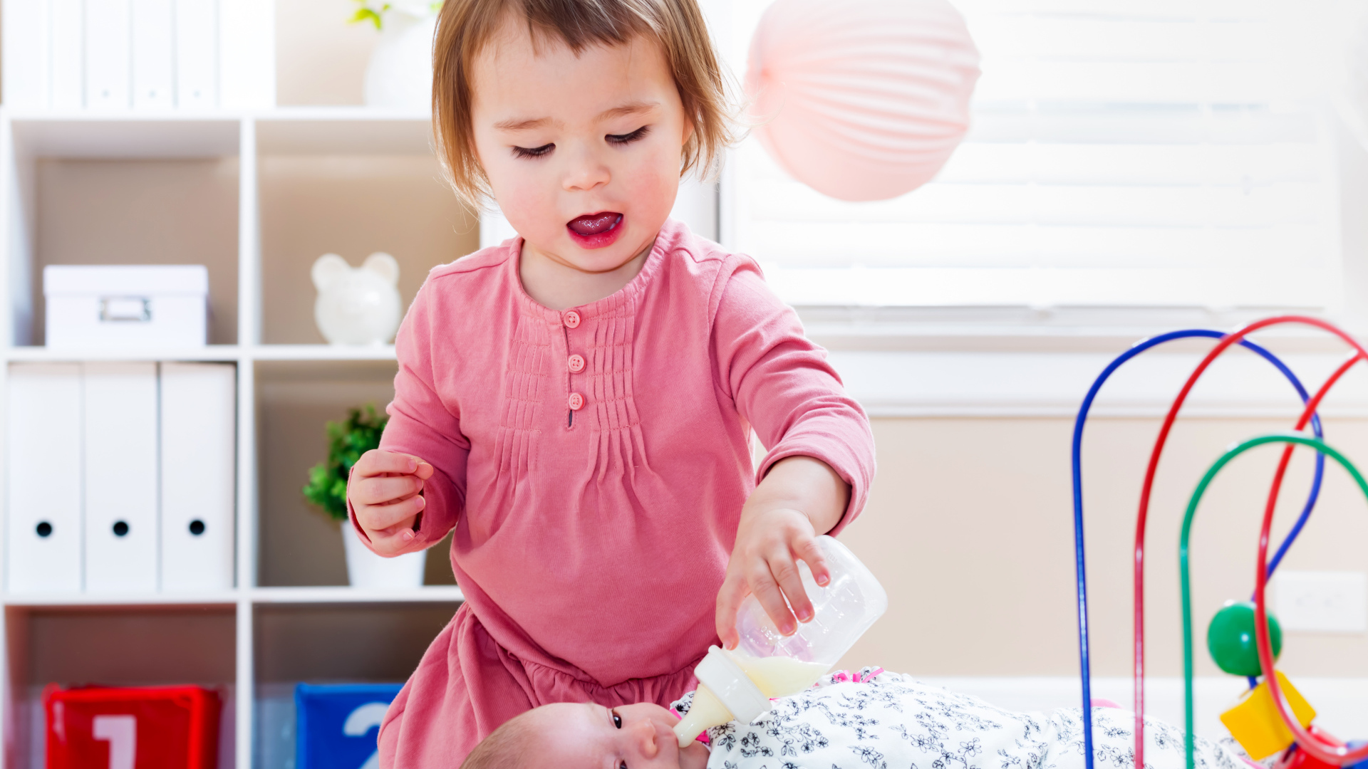 Маленькая девочка кормит из бутылочки маленького брата