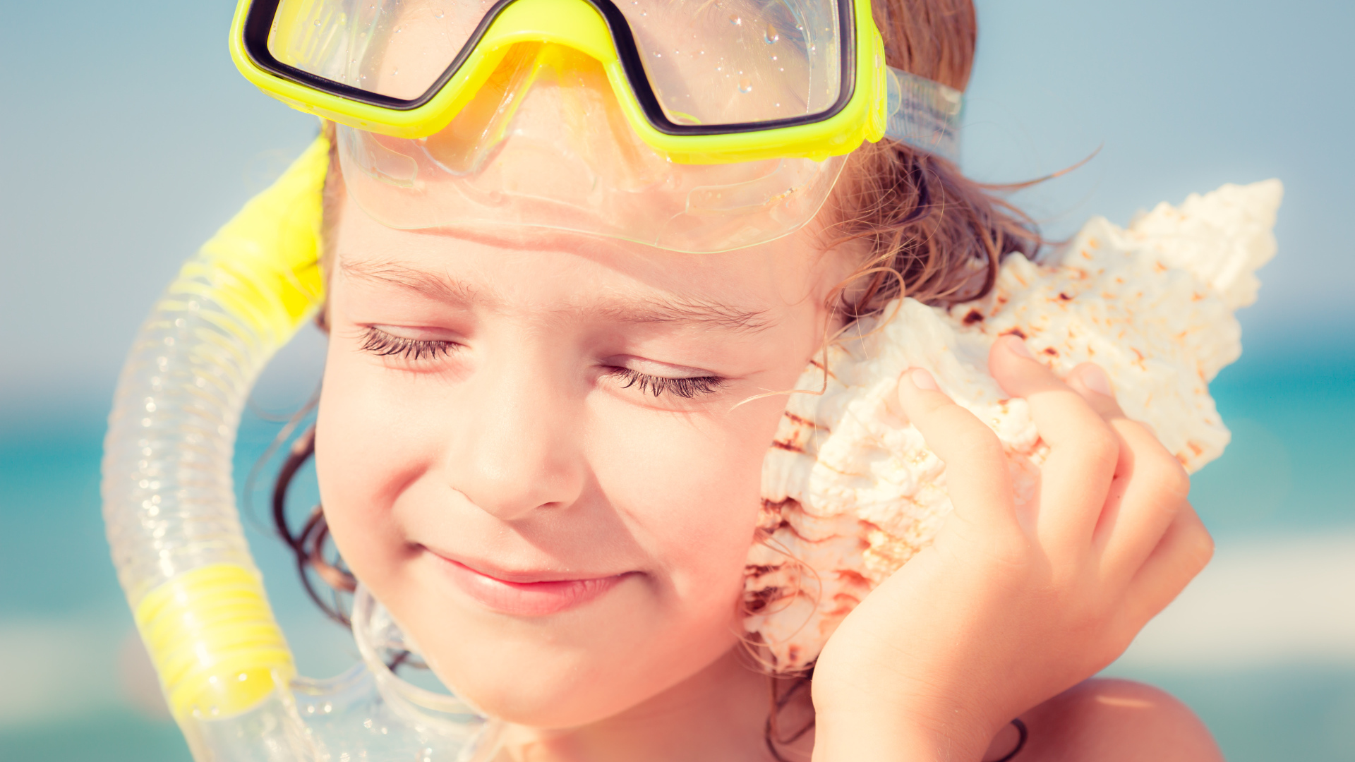 Маленькая девочка приложила ракушку к уху