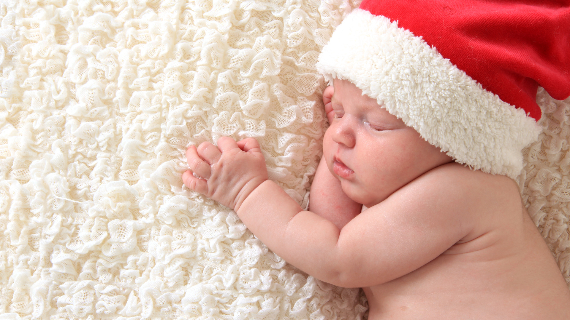 Маленький спящий ребенок в красном новогоднем колпаке