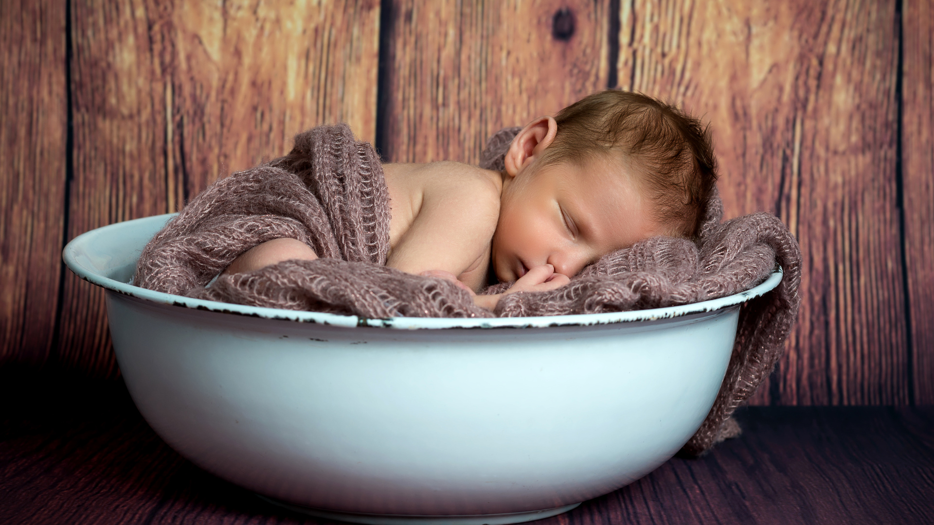 Новорожденный ребенок спит в белой миске