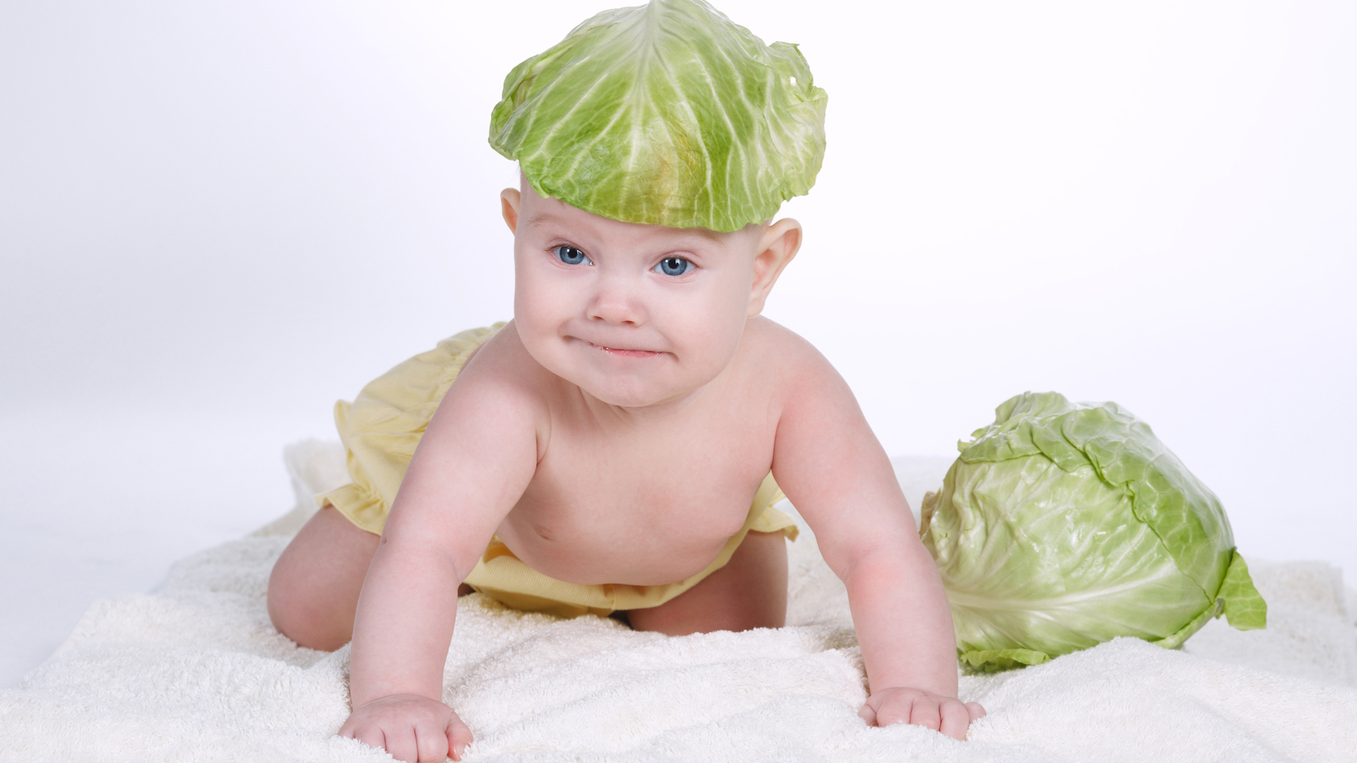 Маленький грудной ребенок с капустным листом на голове