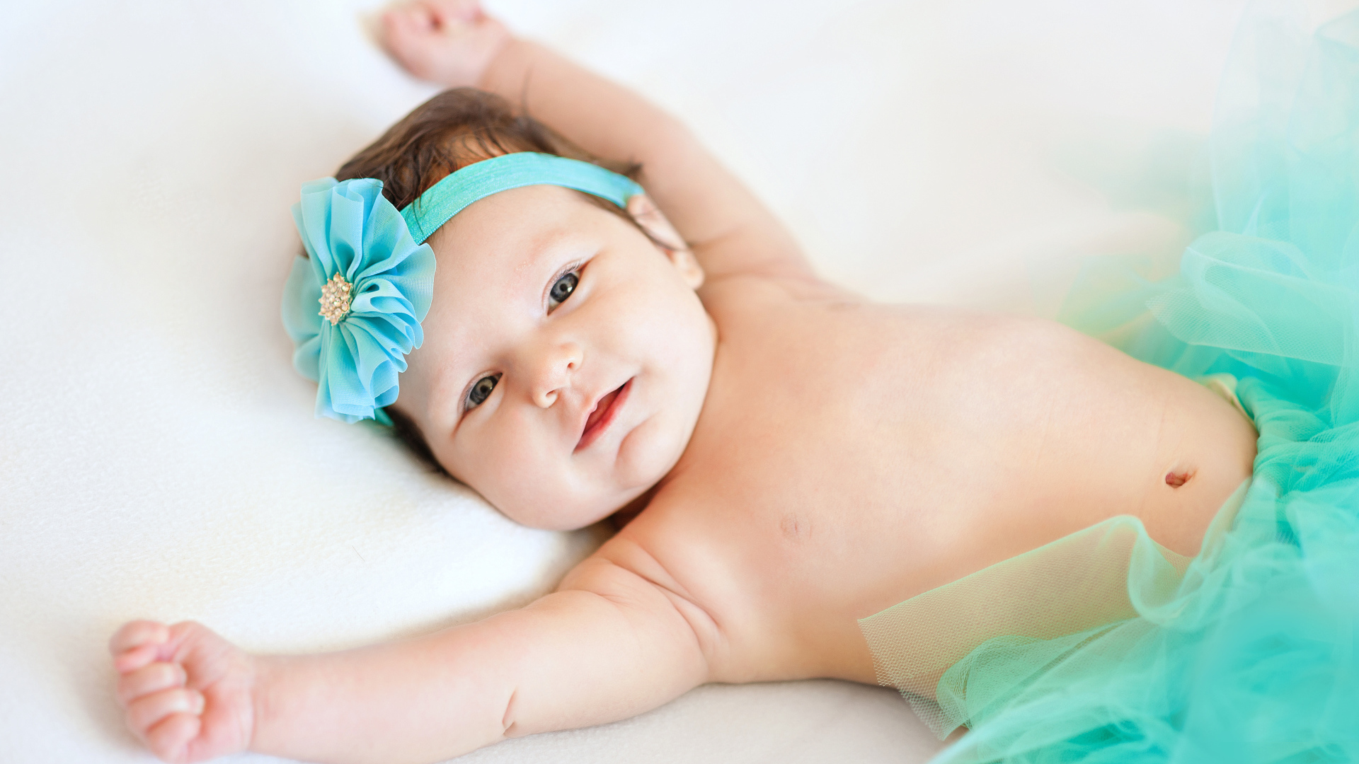 Милая маленькая малышка с цветком бирюзового цвета на голове