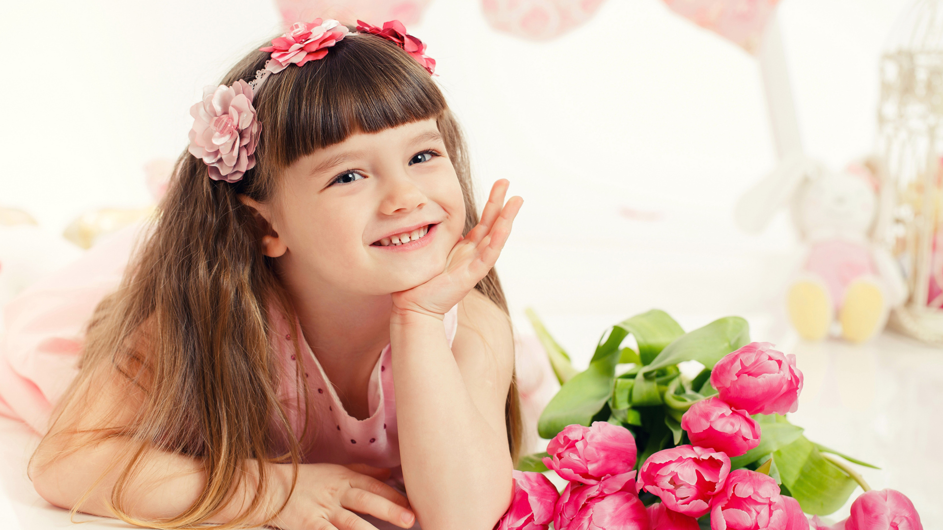 Красивая длинноволосая улыбающаяся девочка с букетом розовых тюльпанов