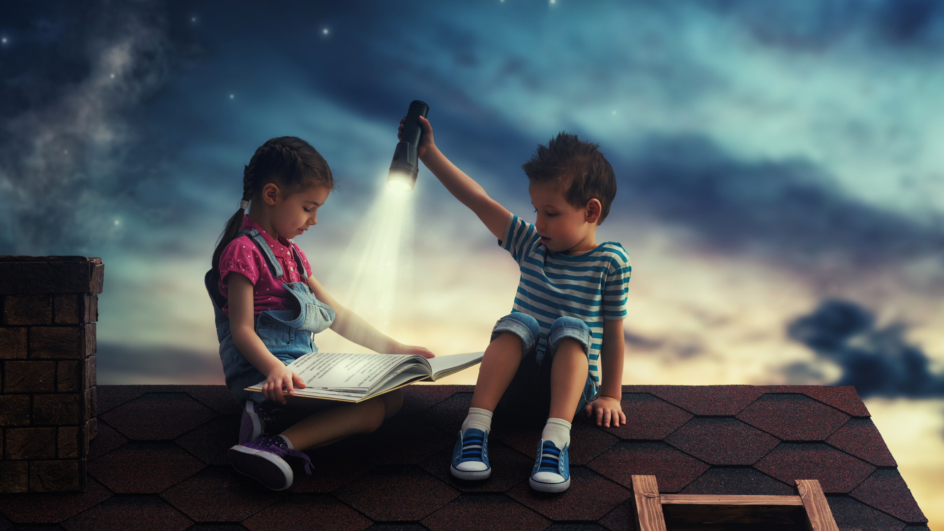 Мальчик и девочка ночью читают книгу на крыше