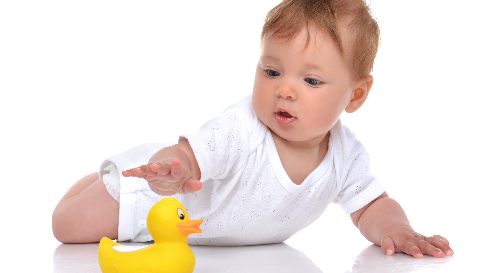 Грудной ребенок с желтой резиновой уточкой на белом фоне
